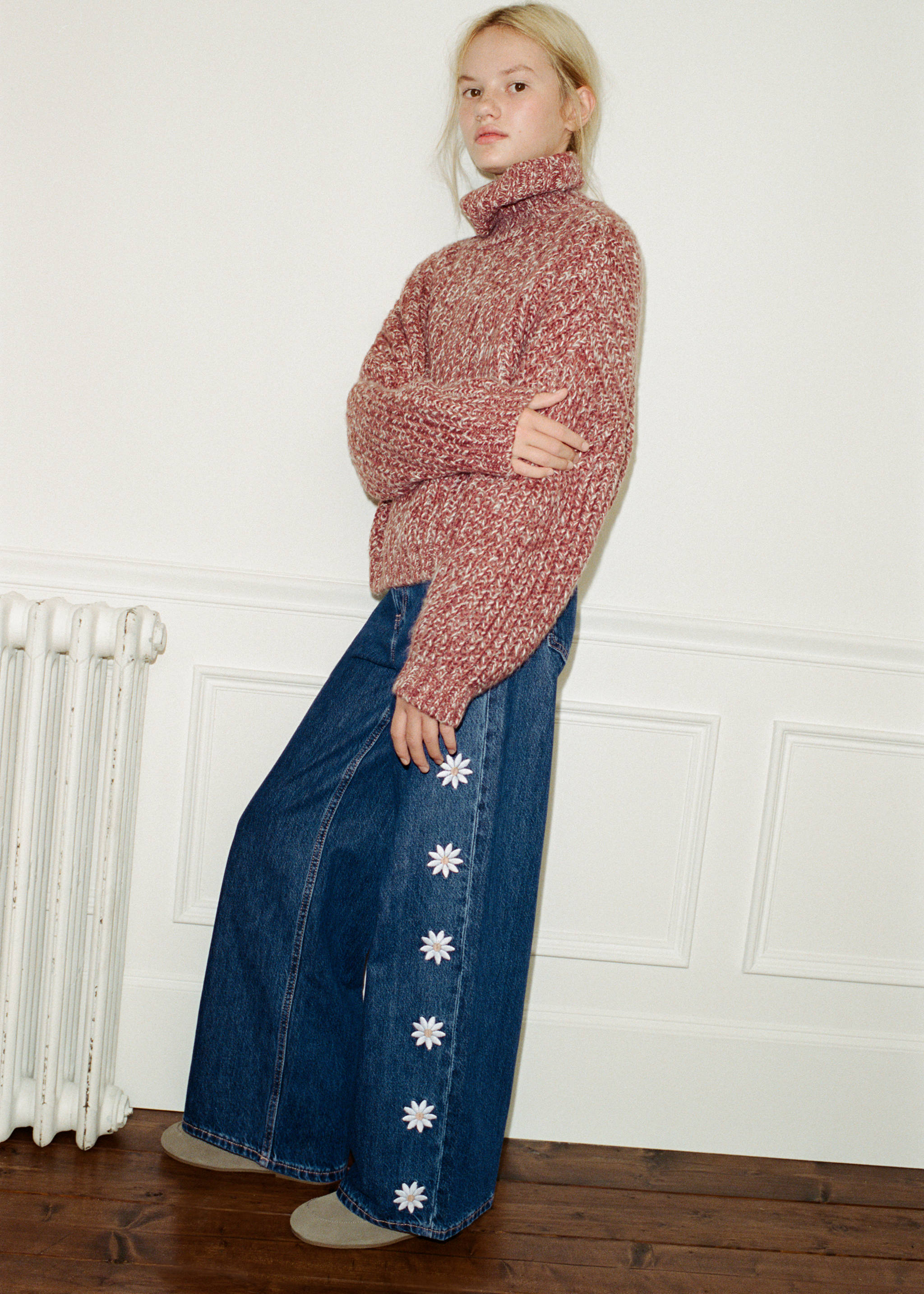 Blue denim trousers with white embroidered daisy appliqués along the leg.