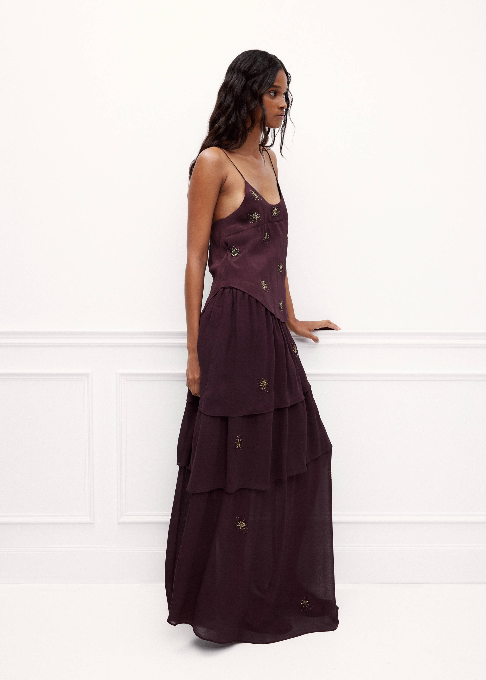 Long plum-coloured tiered skirt with embroidered details, worn with a matching top.