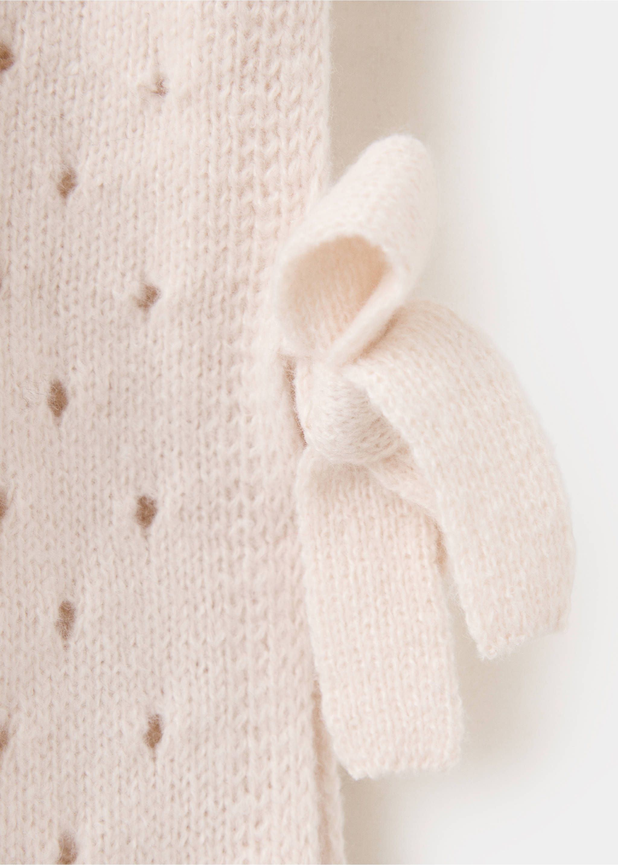 Close-up of a cream knitted vest side tie detail., Ivory White. Ref: 37068277-00.