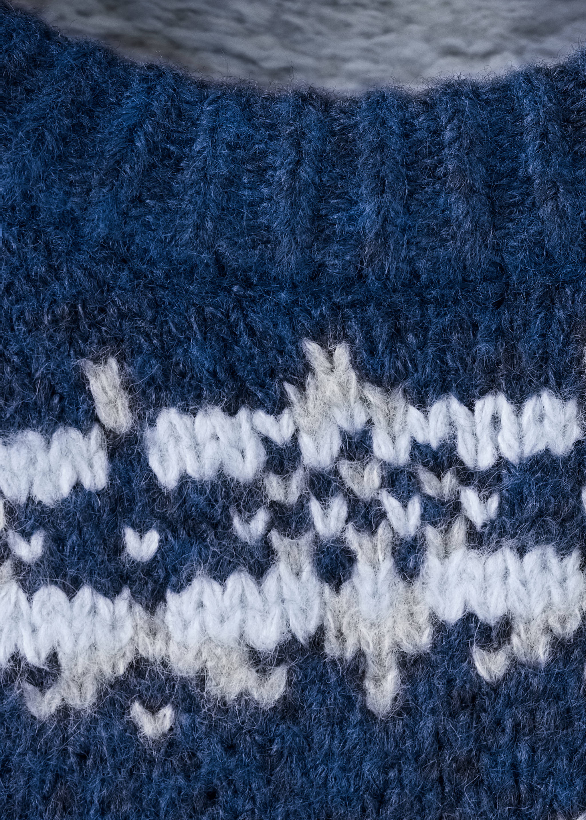 Close-up of a dark blue knitted jumper with a white Nordic pattern.