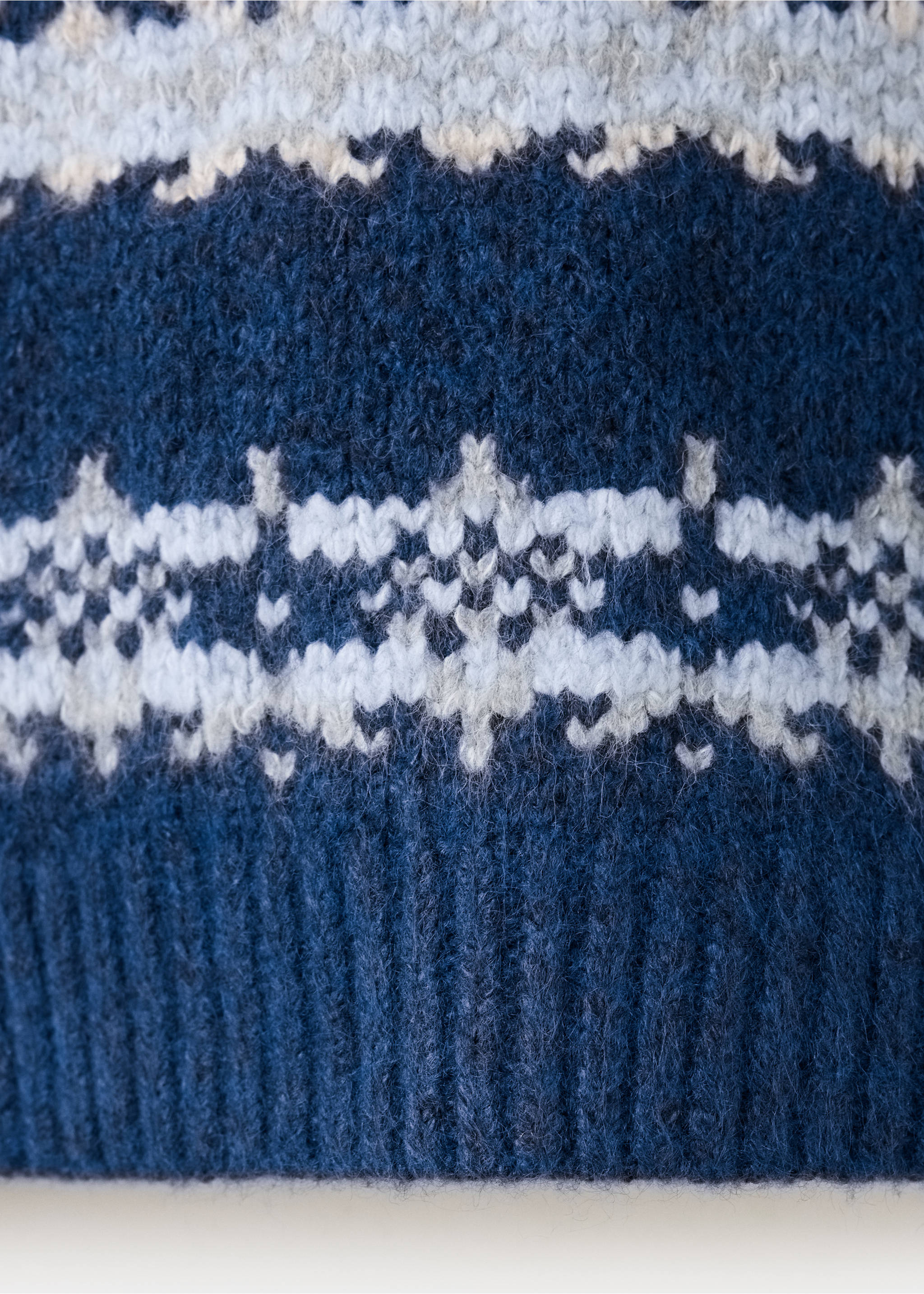 Close-up of a blue knit jersey featuring a white and grey Fair Isle pattern., Indigo Blue. Ref: 37068280-00.