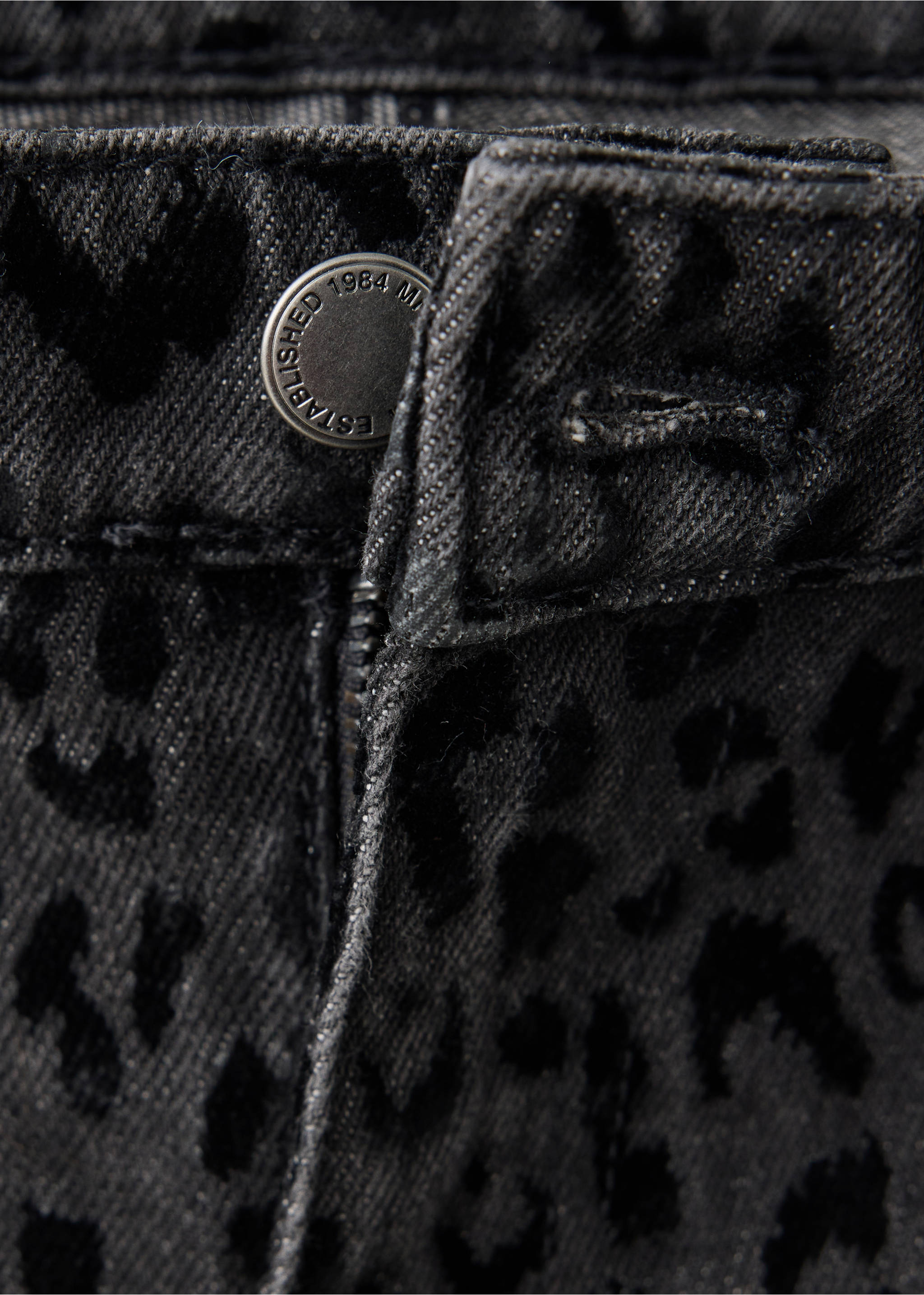 Close-up of dark grey denim trousers featuring an all-over black leopard print and a branded metal button., Denim Grey. Ref: 37068285-00.