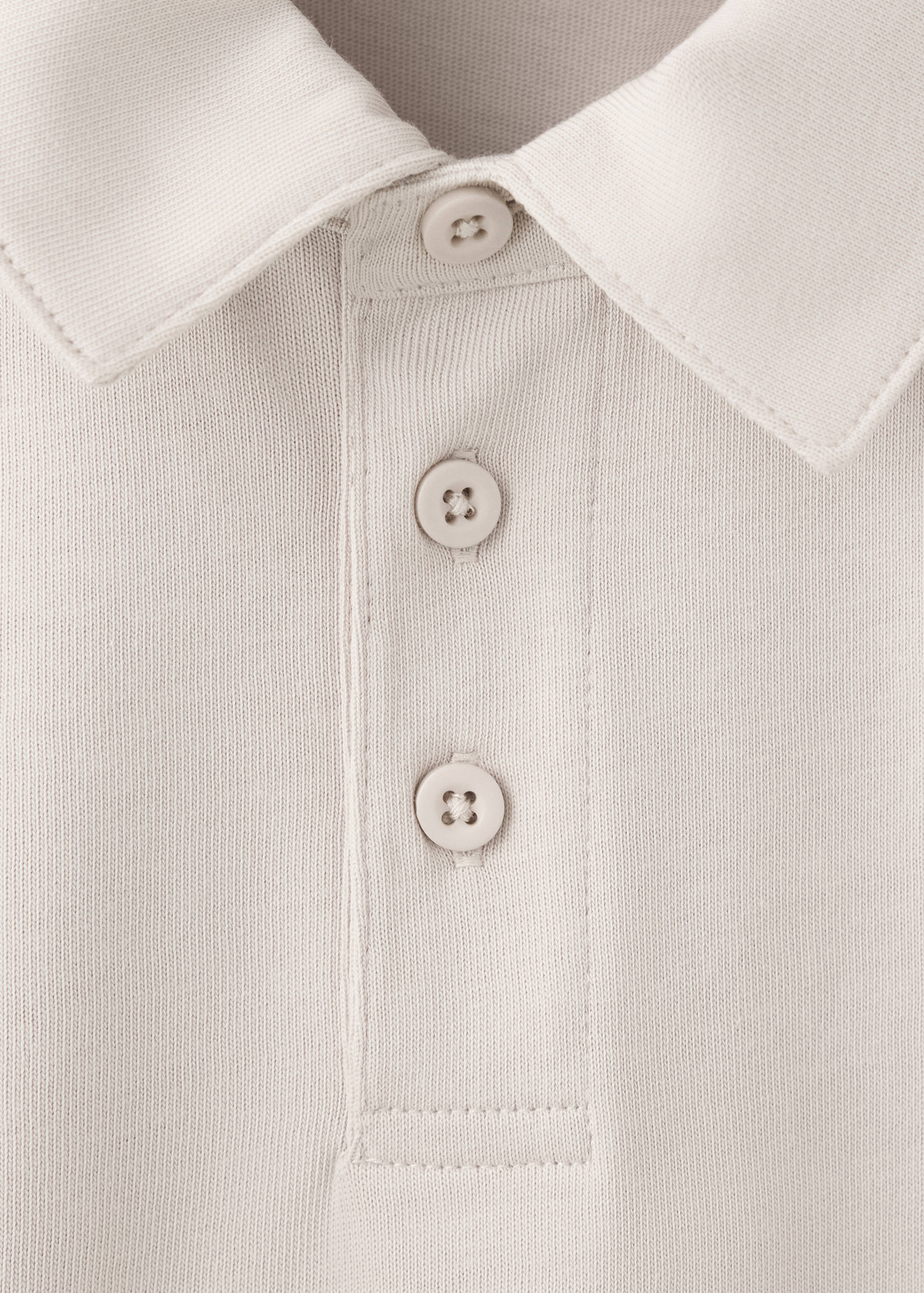 Close-up of a beige kids' polo shirt collar and button placket.