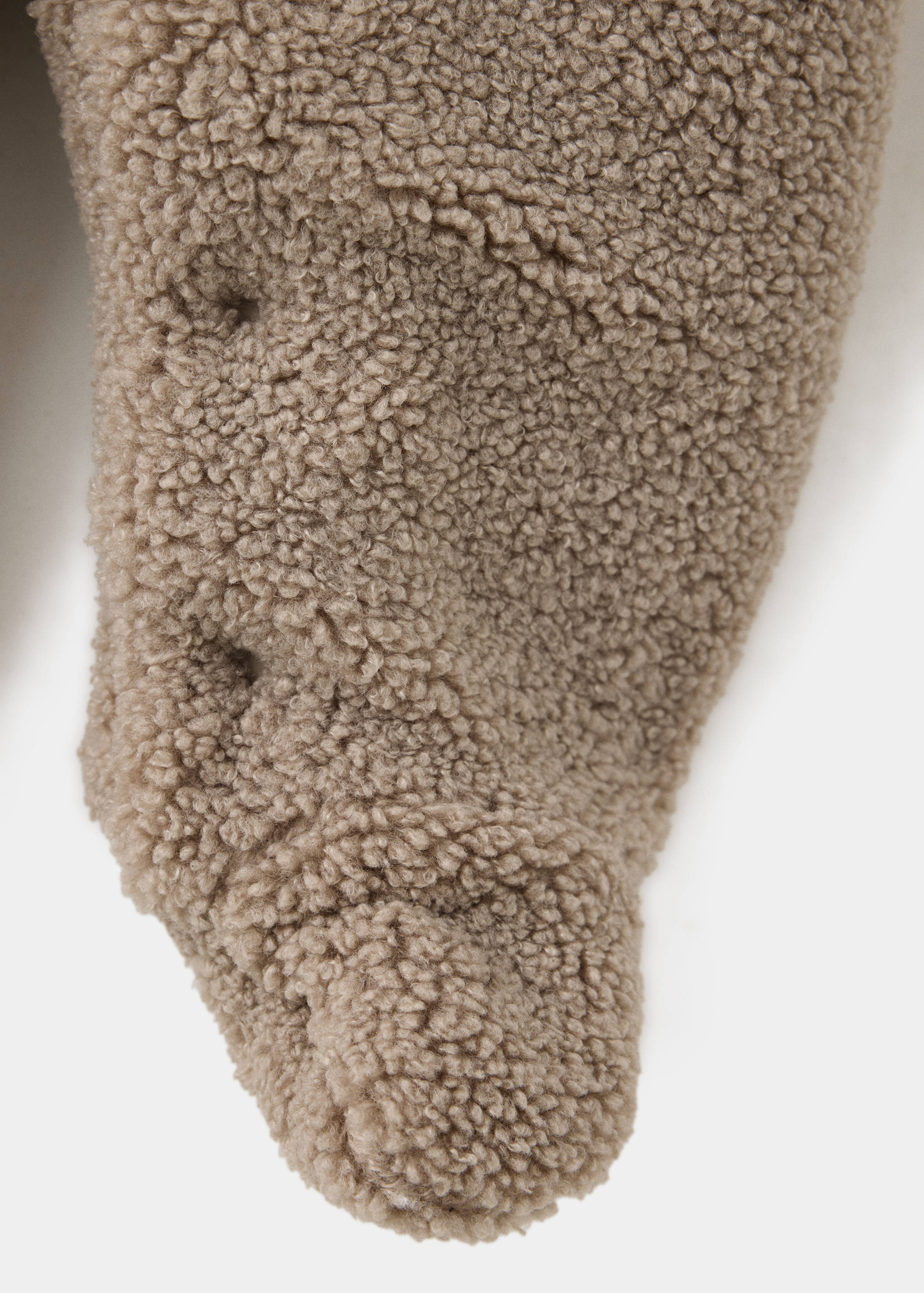 Close-up of the beige faux-shearling coat fabric texture.