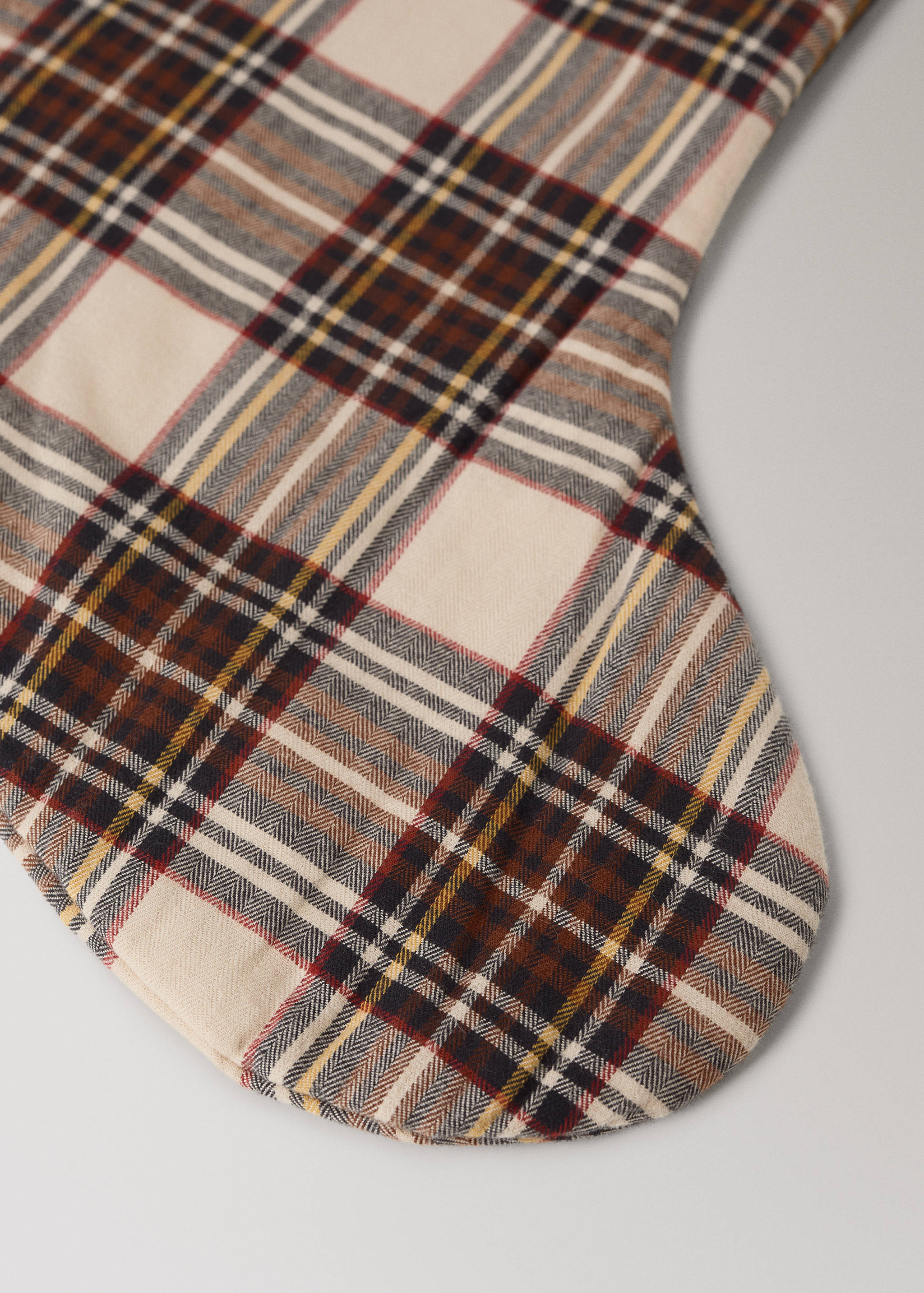 Close-up of a Christmas stocking in a cream, brown, and black tartan plaid.