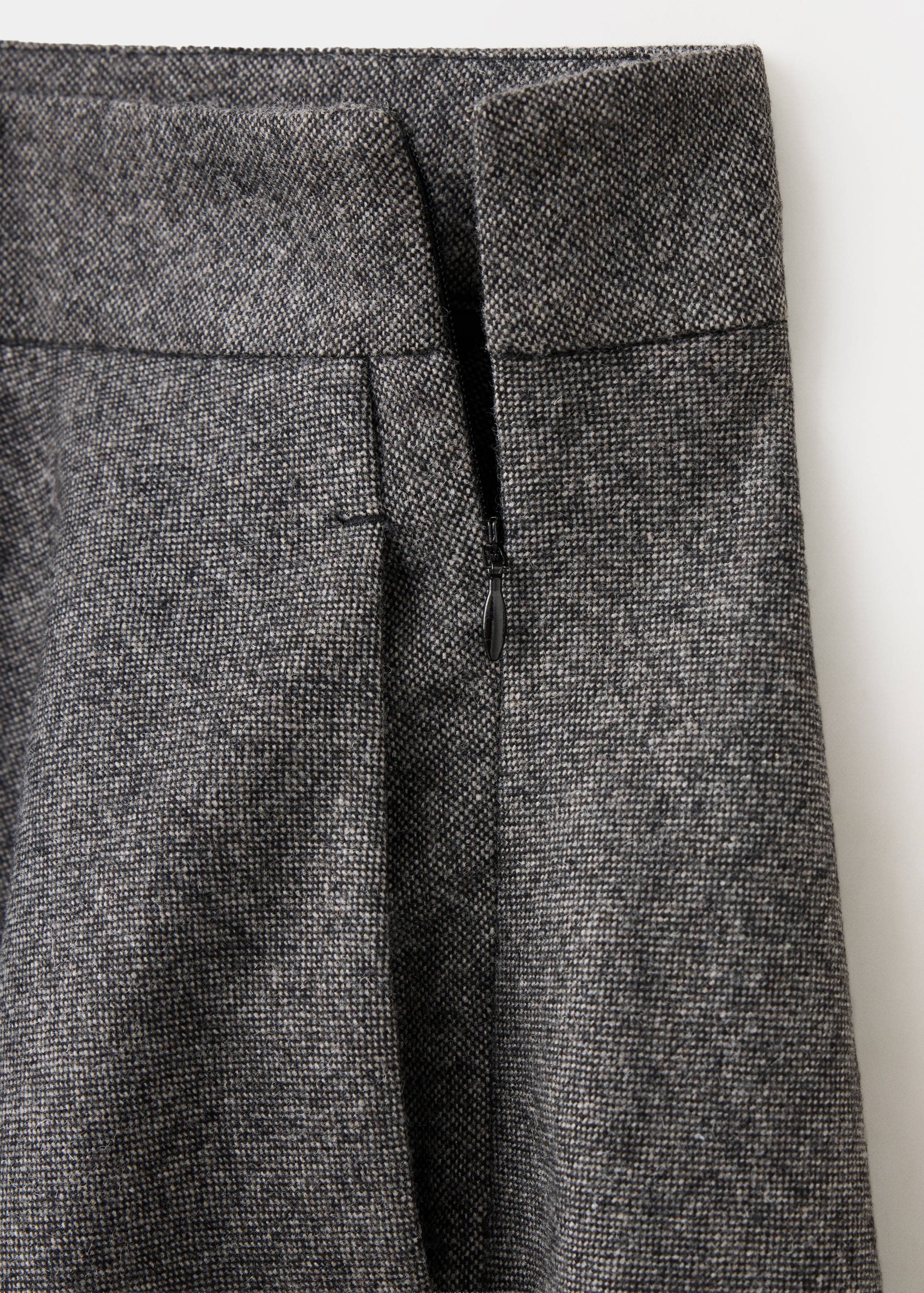 Close-up of a grey tweed skirt showing the waistband and side zip detail.
