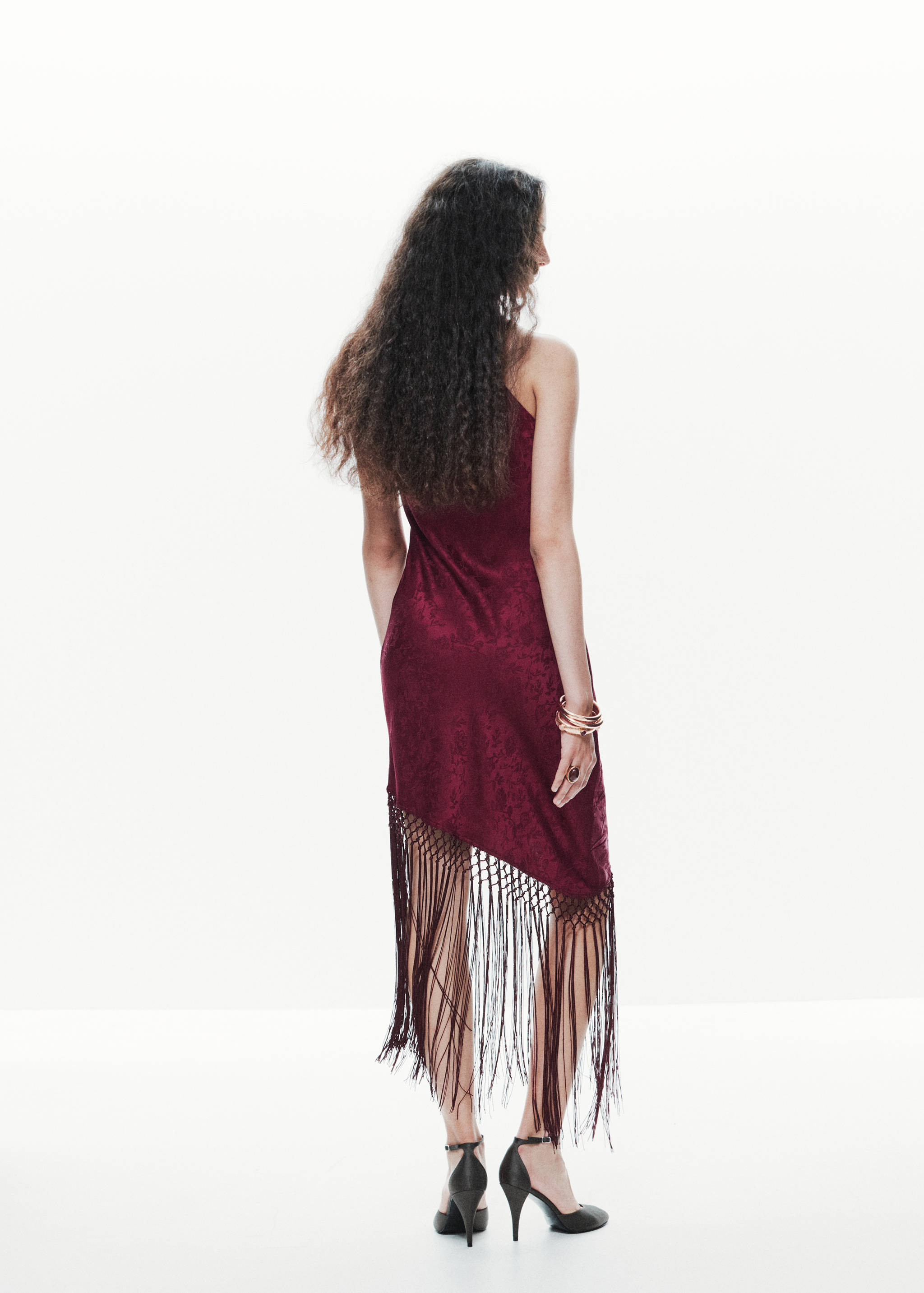 Burgundy velvet midi dress with an asymmetric fringed hem, back view.