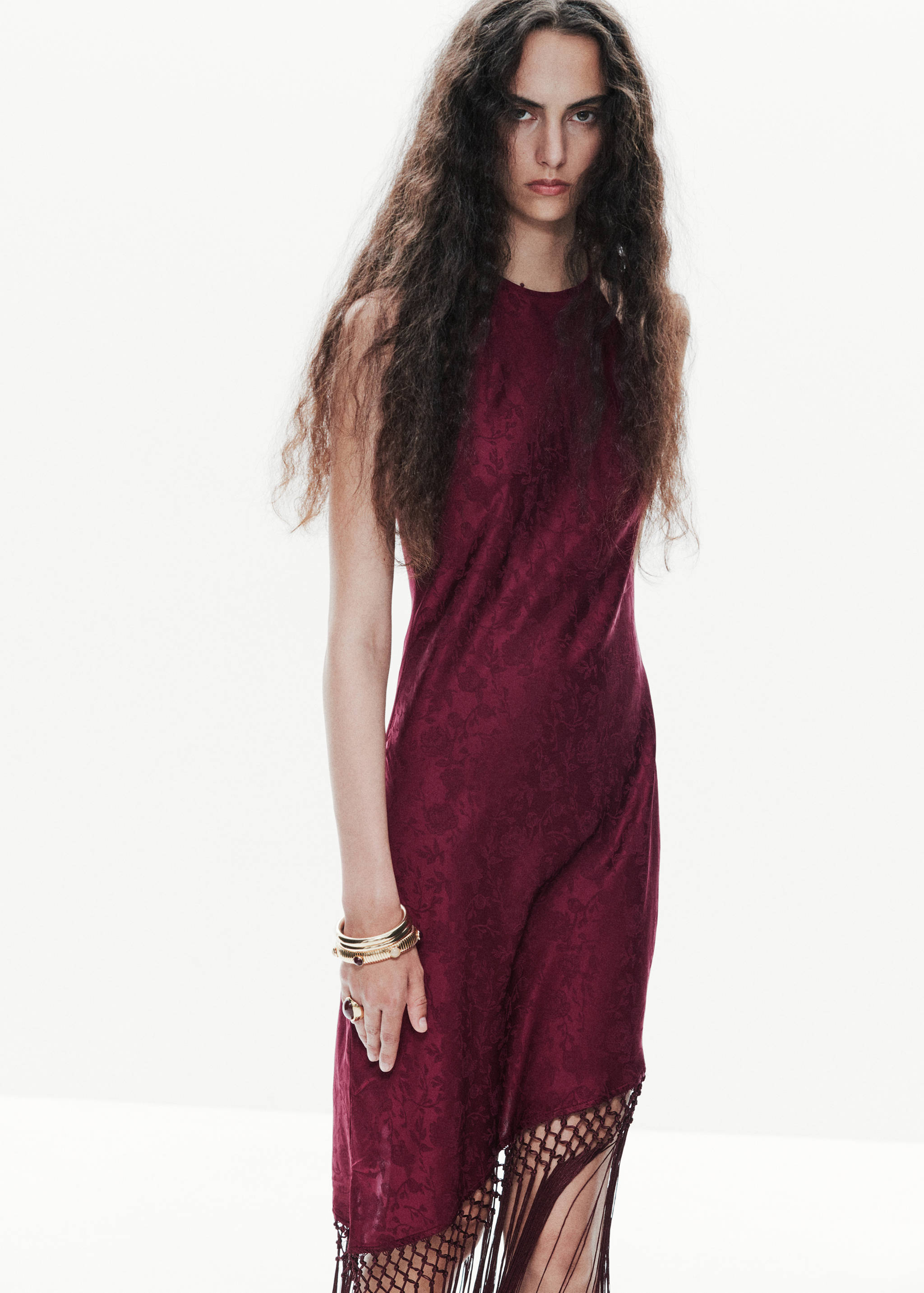 Maroon sleeveless dress with floral pattern, high neckline, and asymmetric fringed hem.