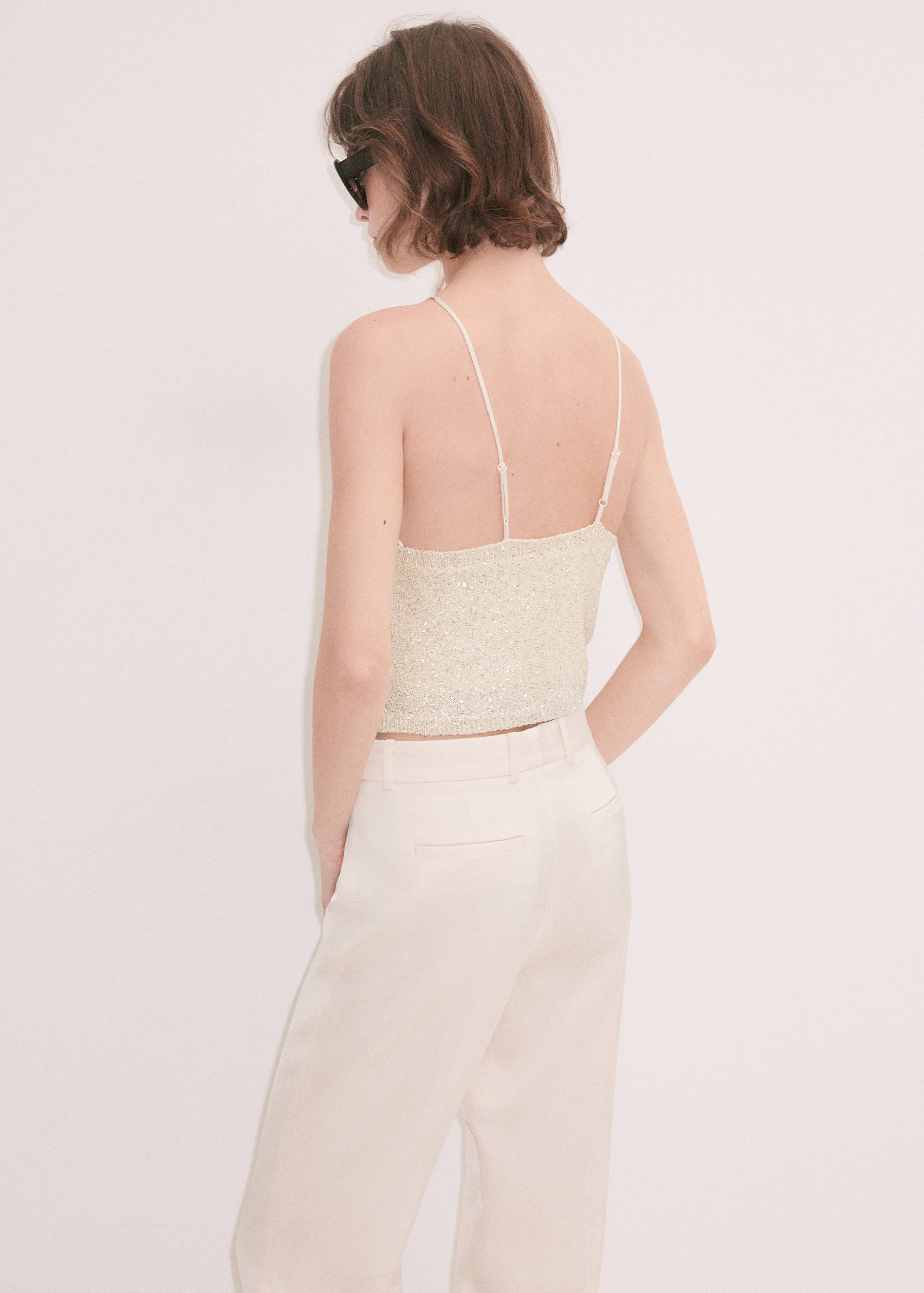 Back view of a cream sequin top with thin spaghetti straps.