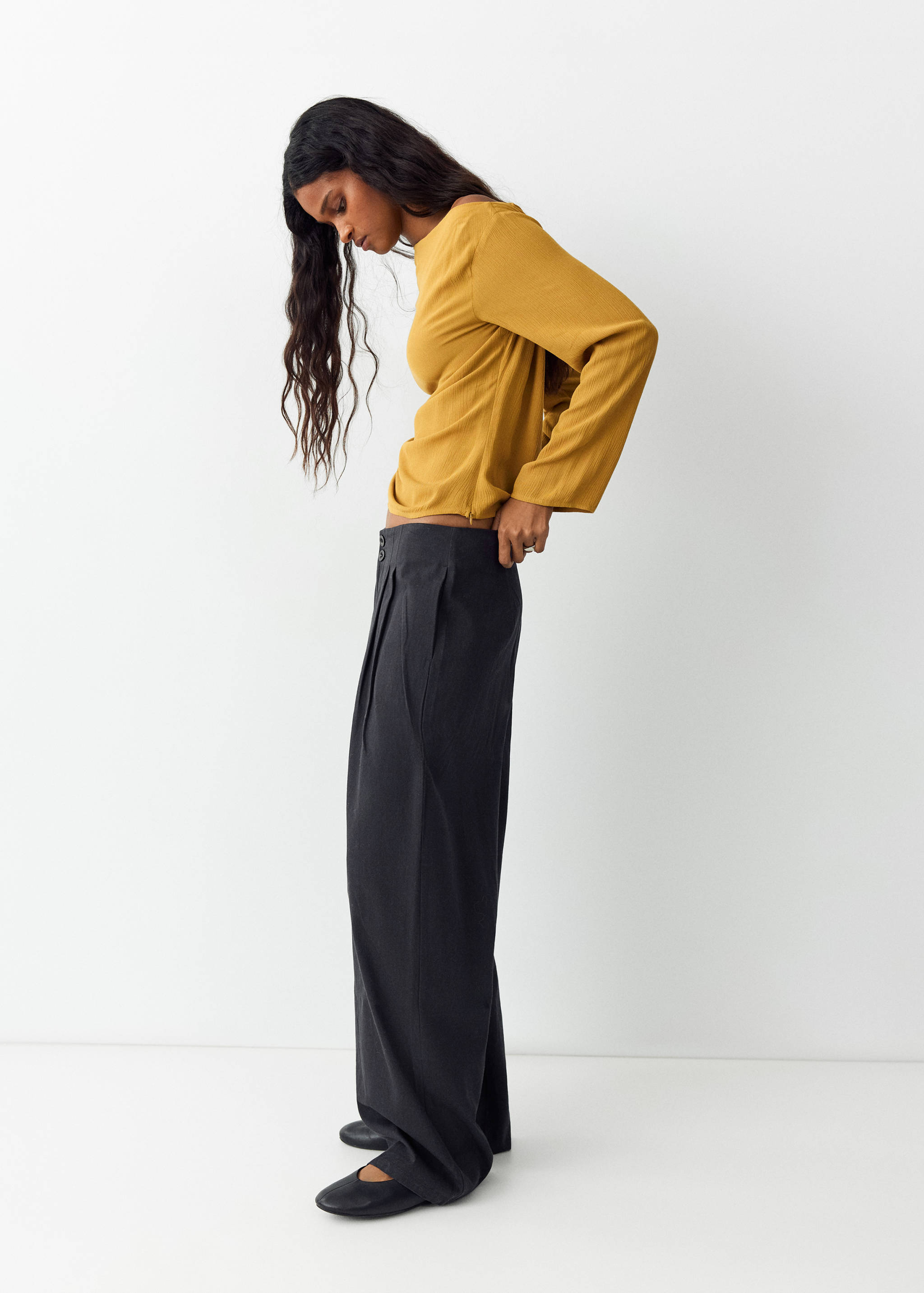 Dark grey high-waisted pleated wide-leg trousers.