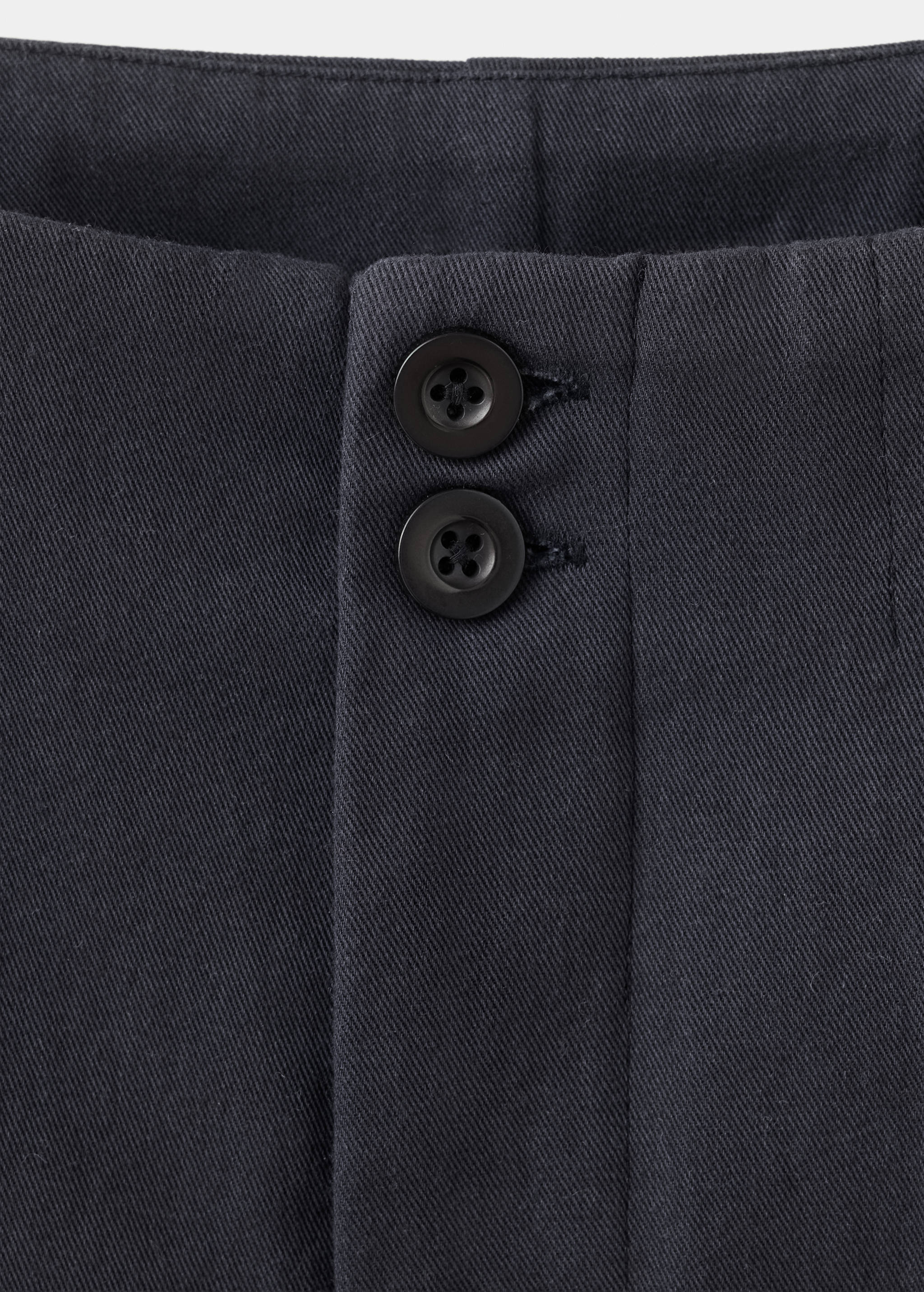 Close-up of dark grey trousers waistband with double-button closure.