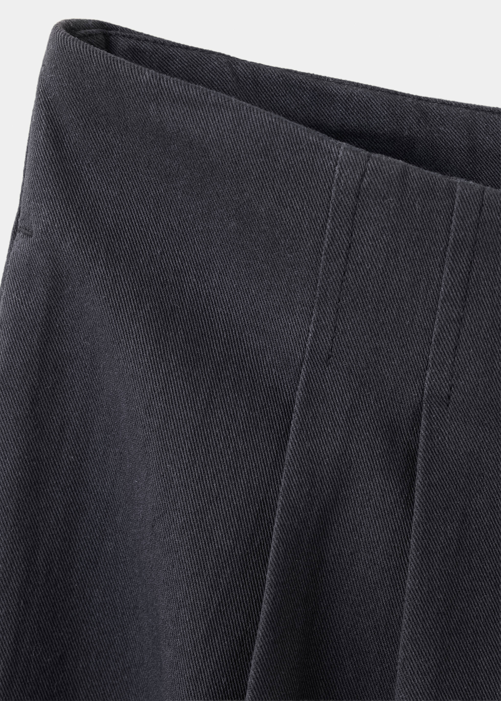 Close-up of dark grey trousers fabric texture and seams.