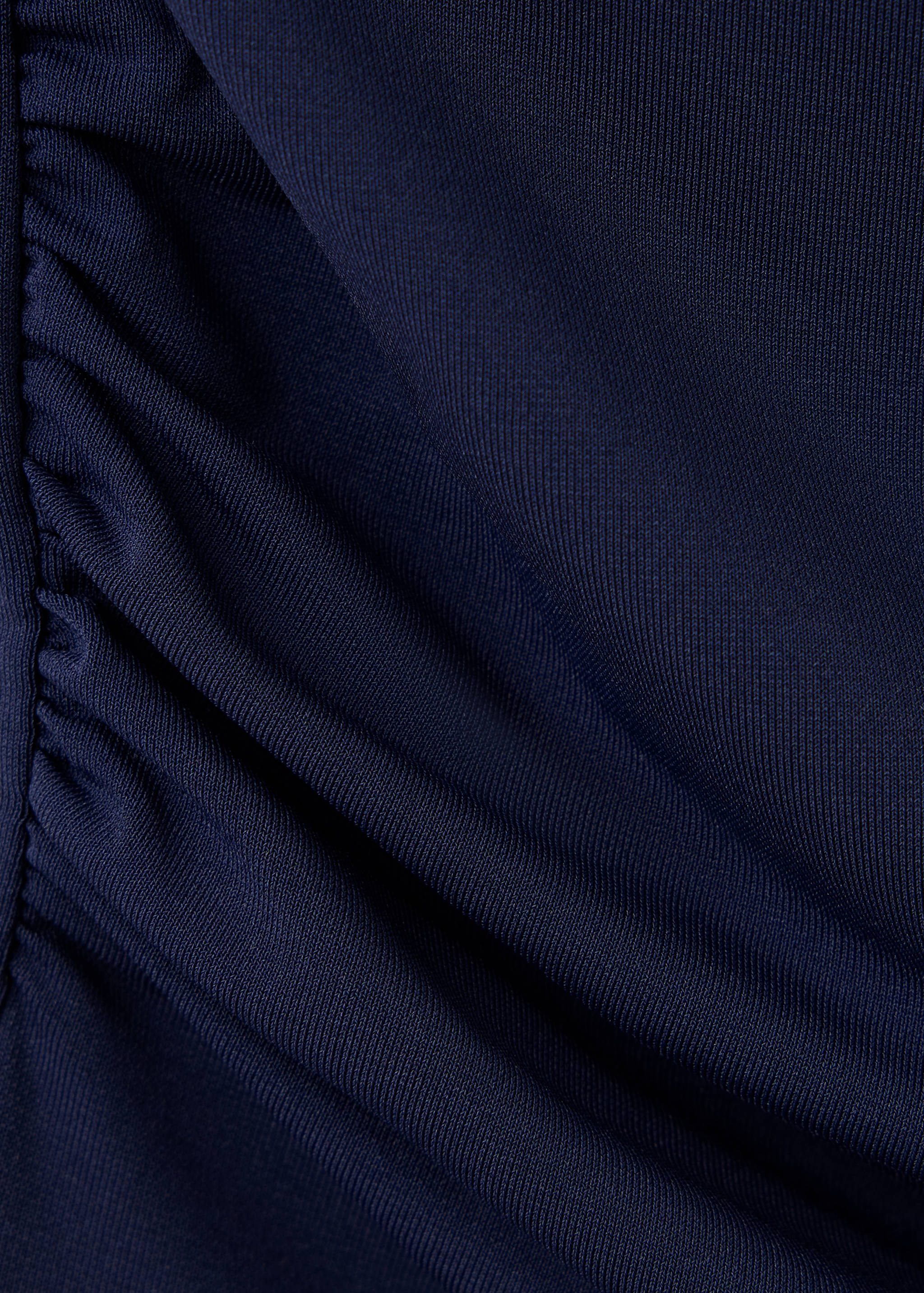 Close-up of navy blue ribbed top fabric with side gathers.