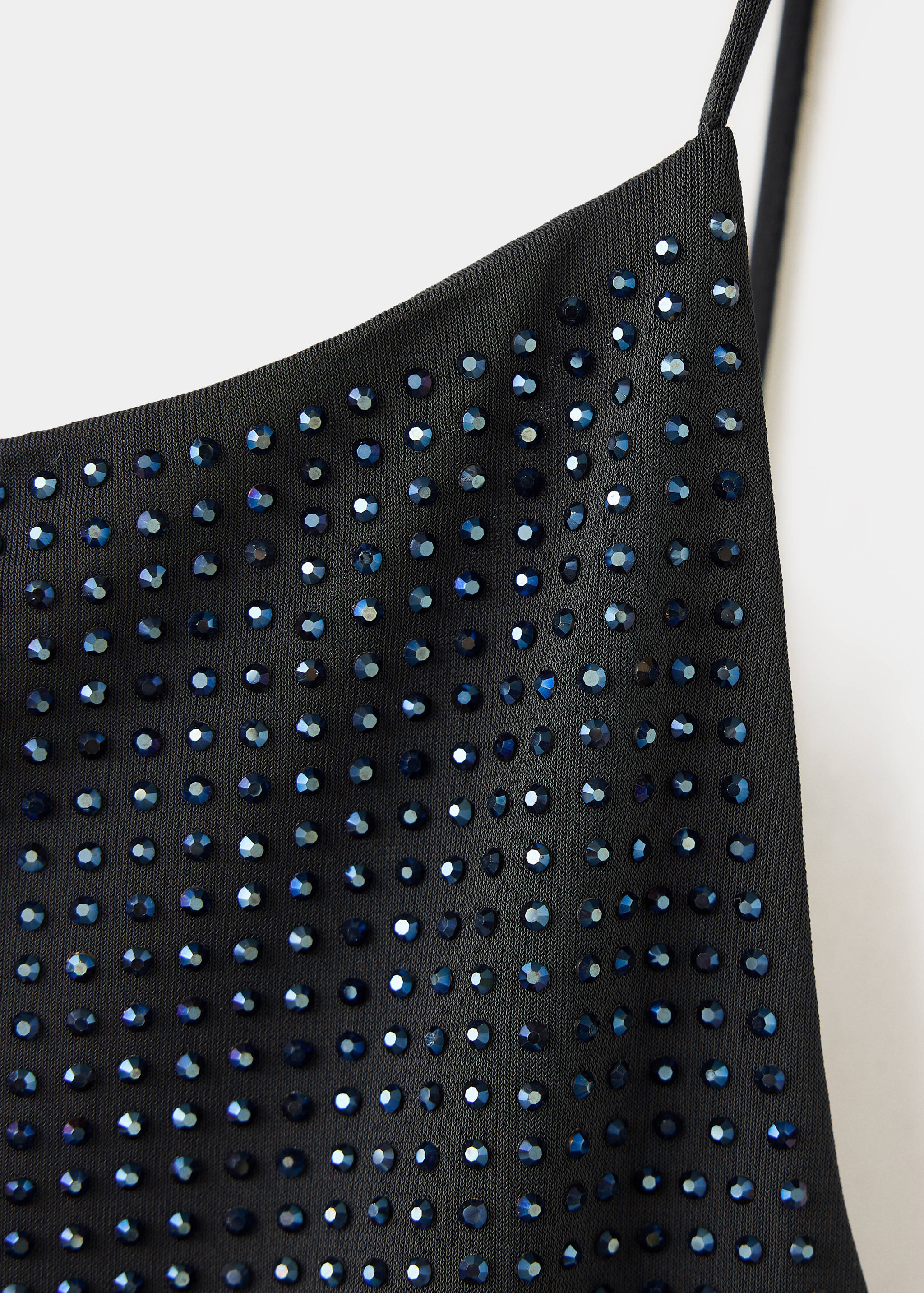 Close-up of a black top with thin straps and blue rhinestone embellishments.