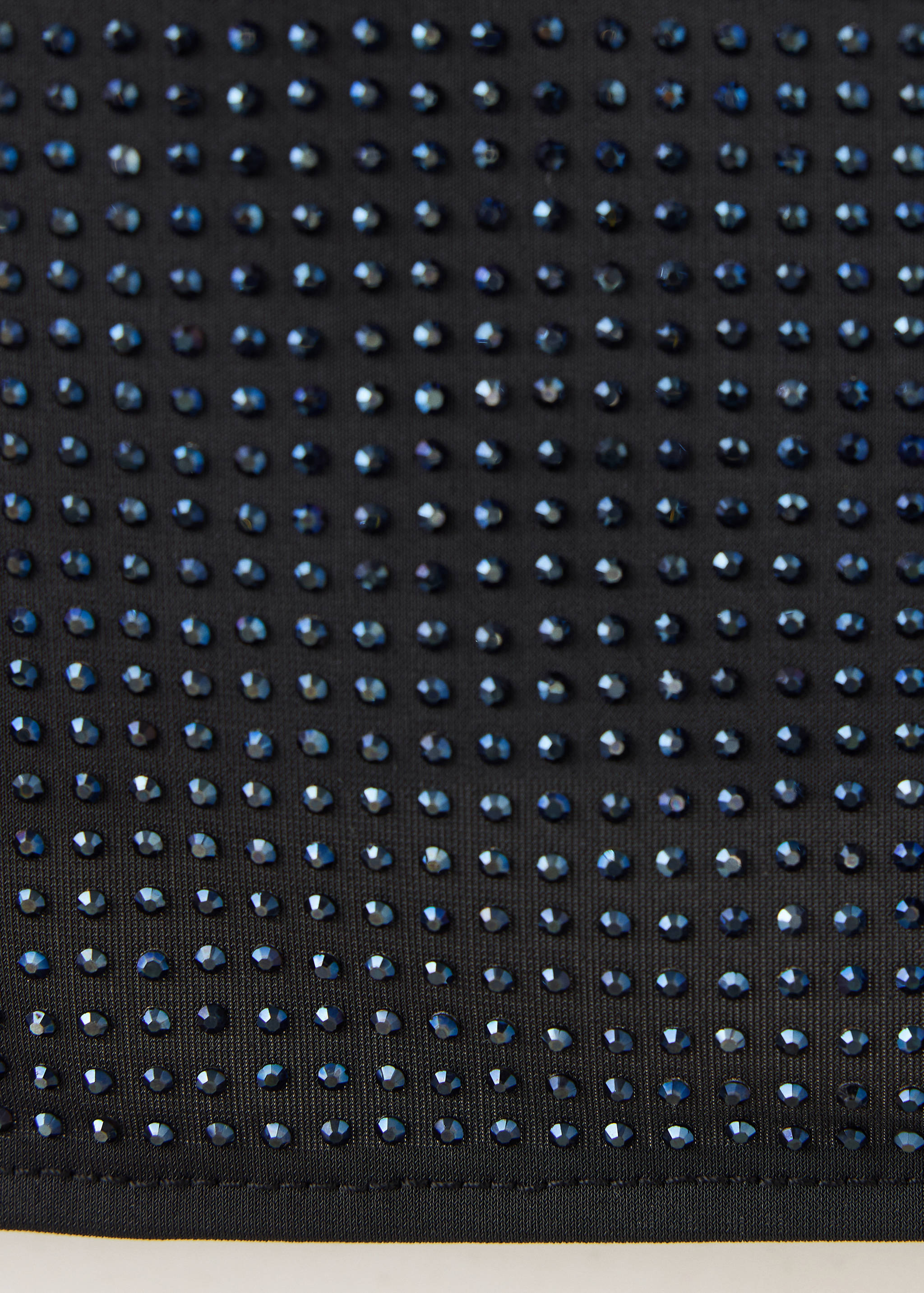 Close-up of a black top embellished with small dark rhinestones.