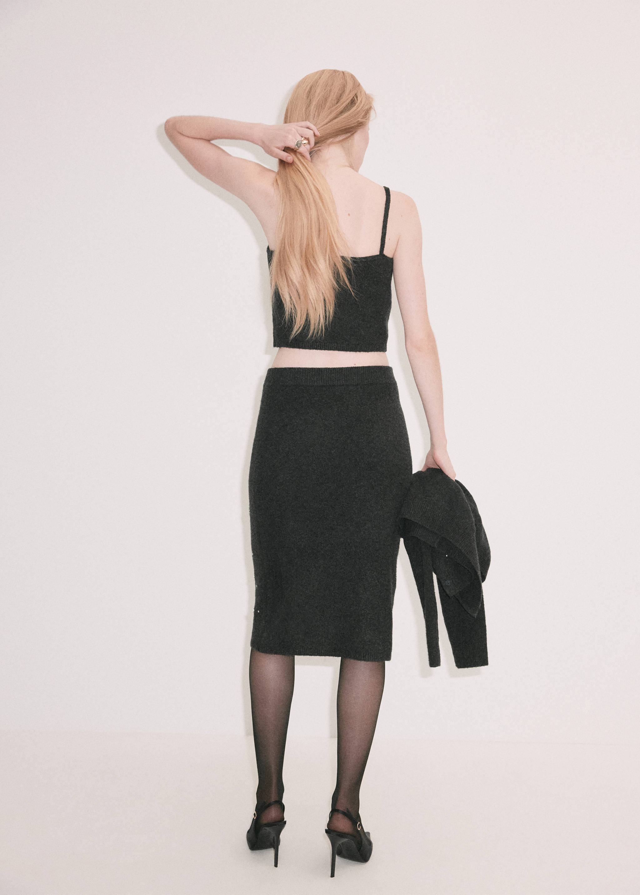 Dark grey knitted crop top from the back, worn with a matching skirt.