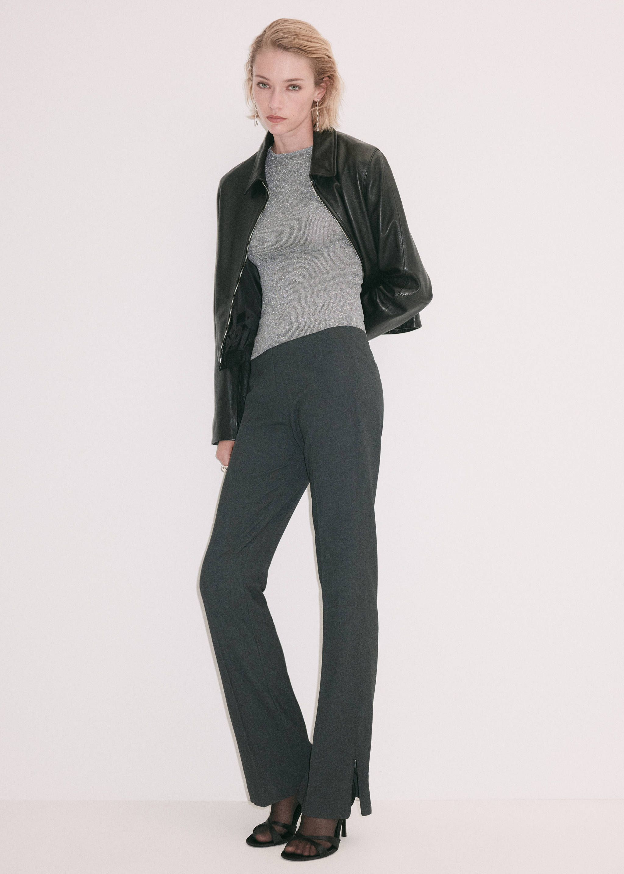 Grey shimmer fitted top worn with a black jacket and grey trousers.