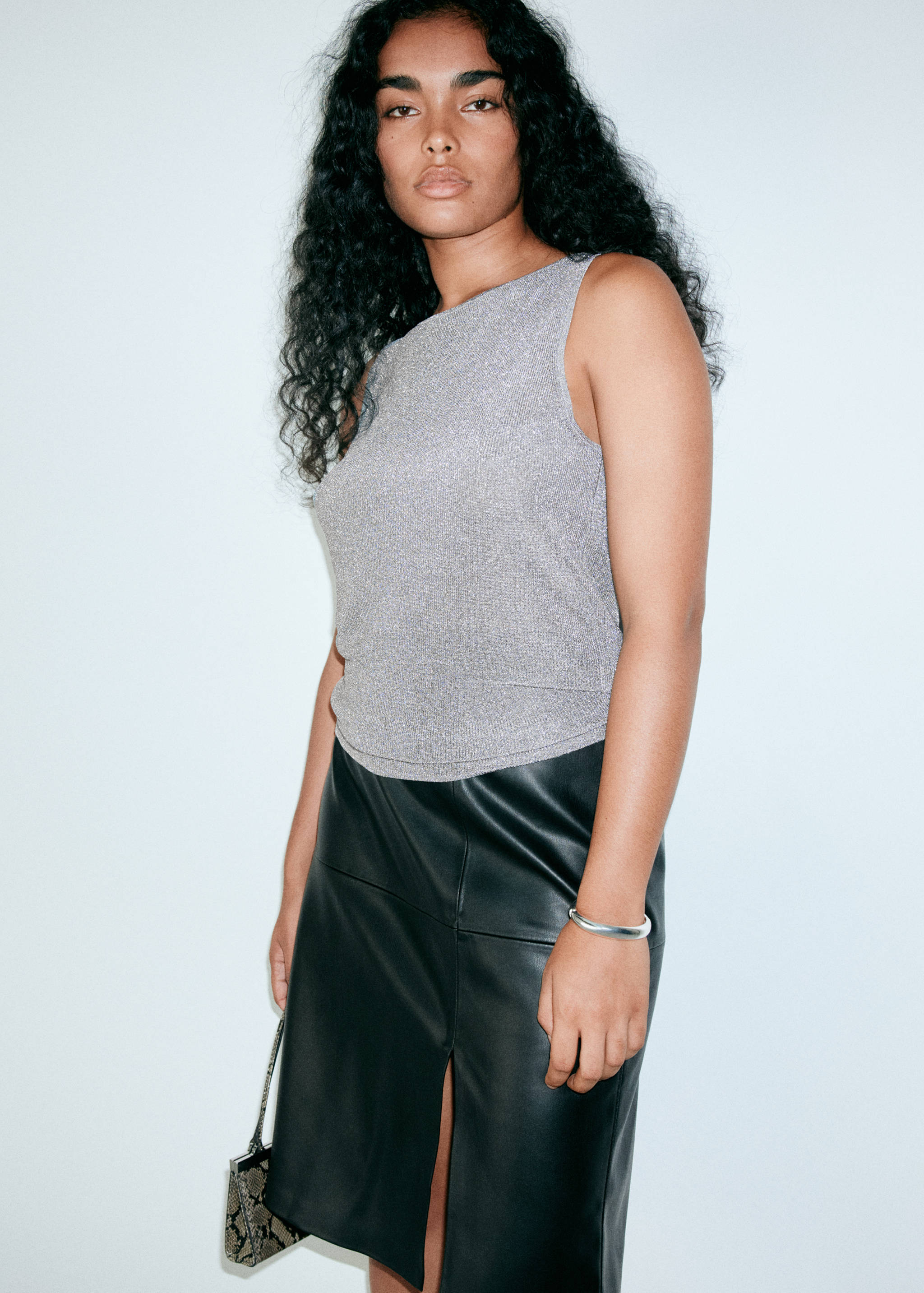 Silver metallic sleeveless top with a boat neckline, paired with a black skirt.