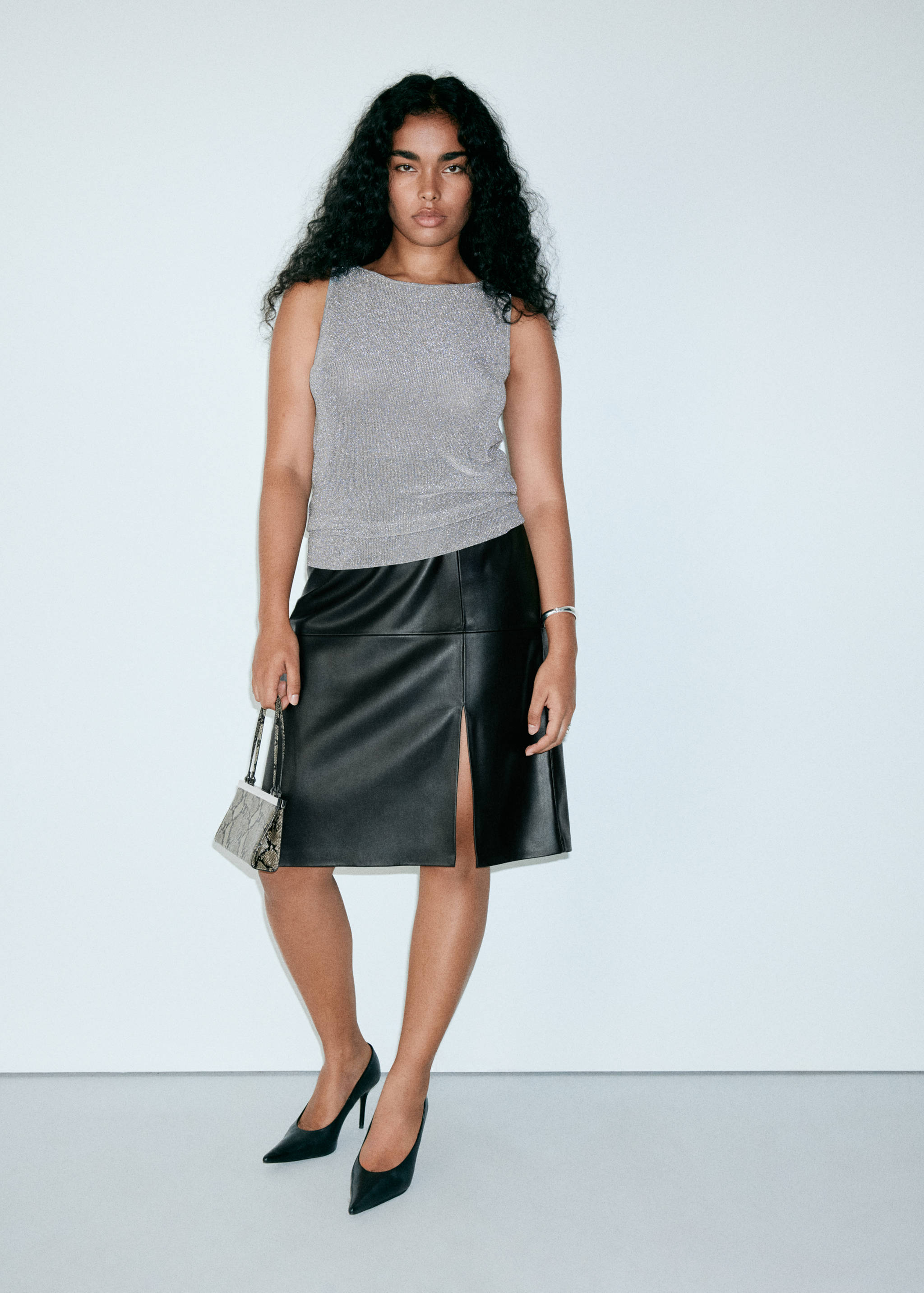 Sleeveless metallic grey top worn with a black faux-leather midi skirt.