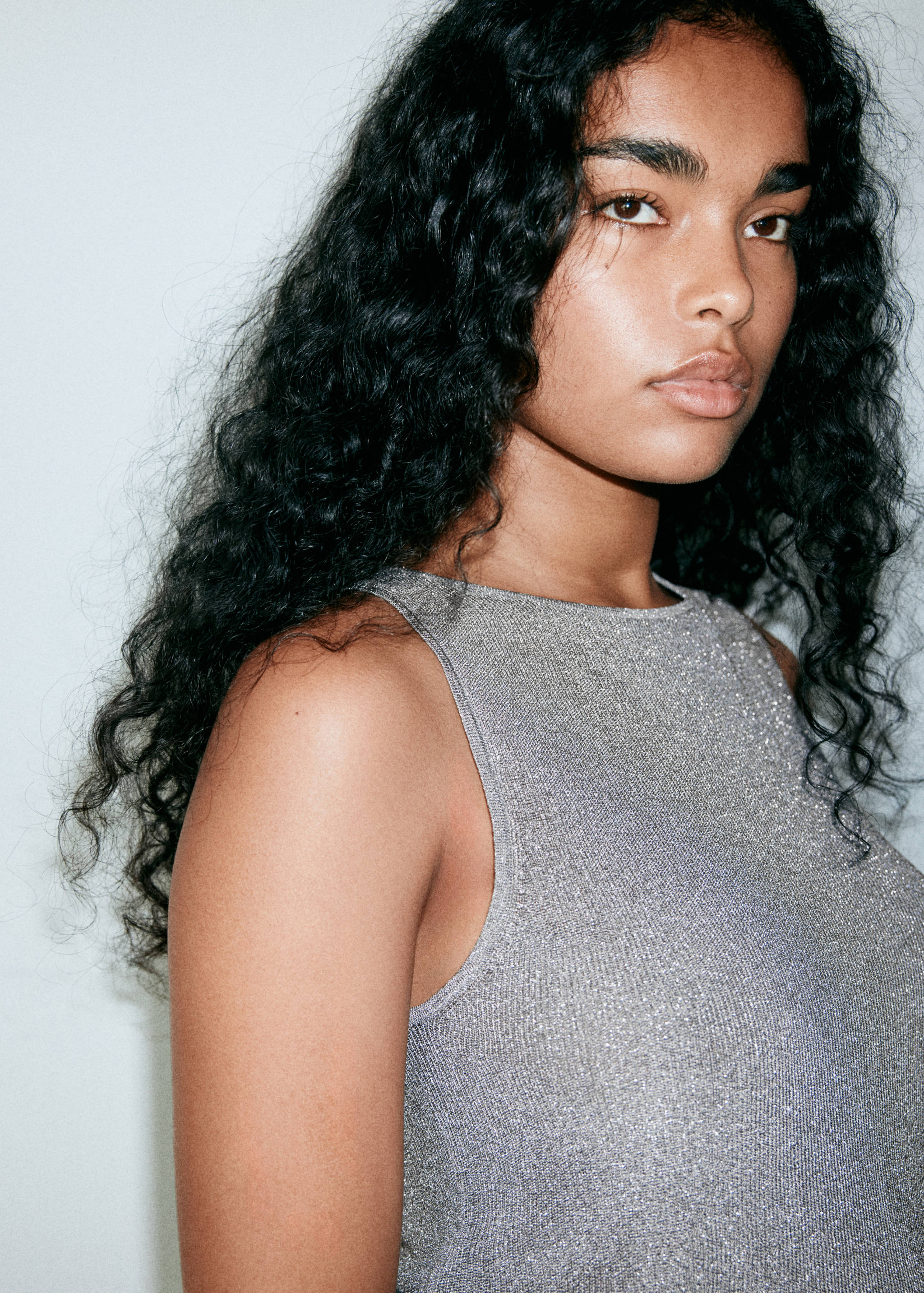 Metallic silver sleeveless knit top with a rounded neckline.