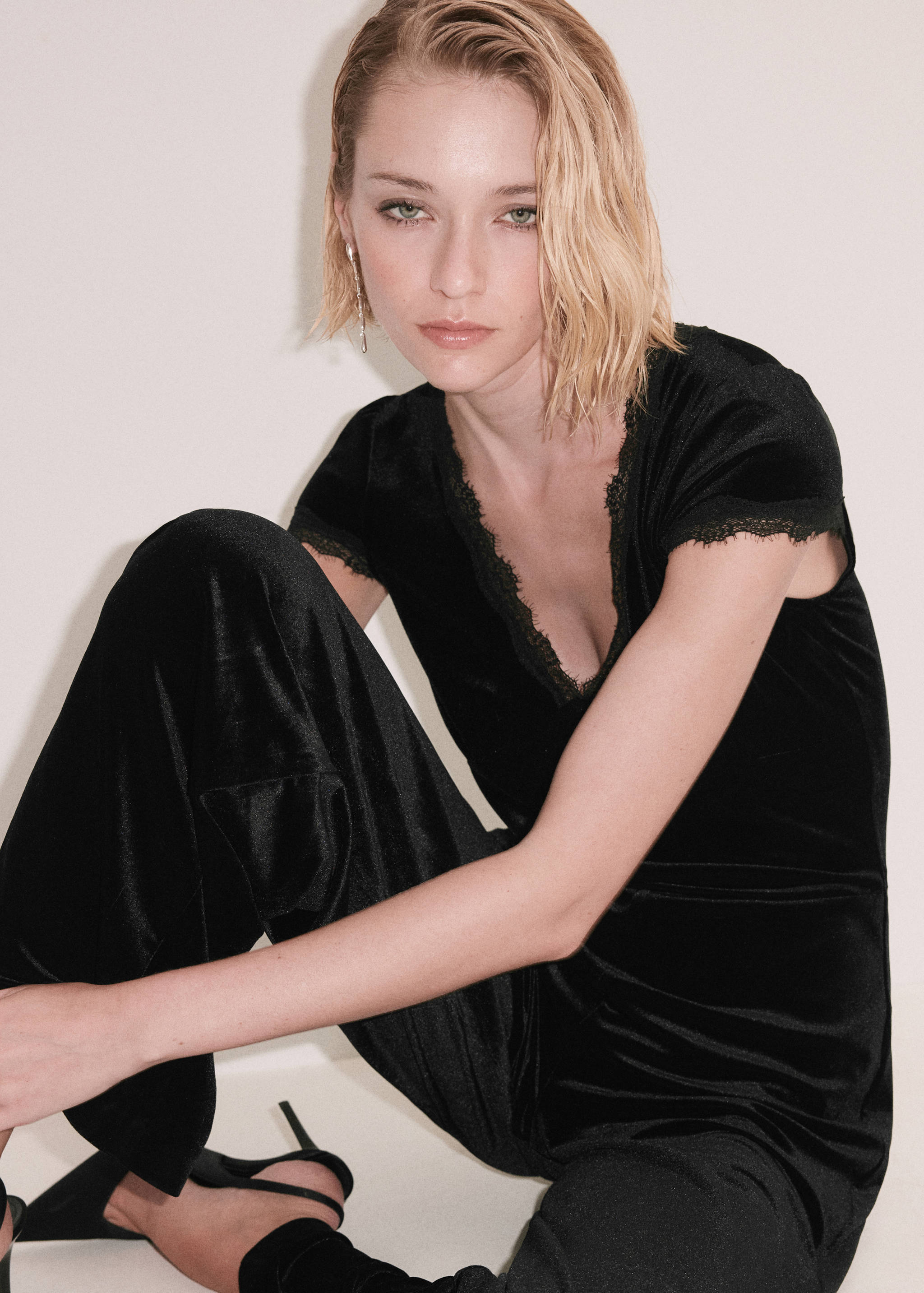 Black velvet jumpsuit with a lace-trimmed V-neck and short sleeves.
