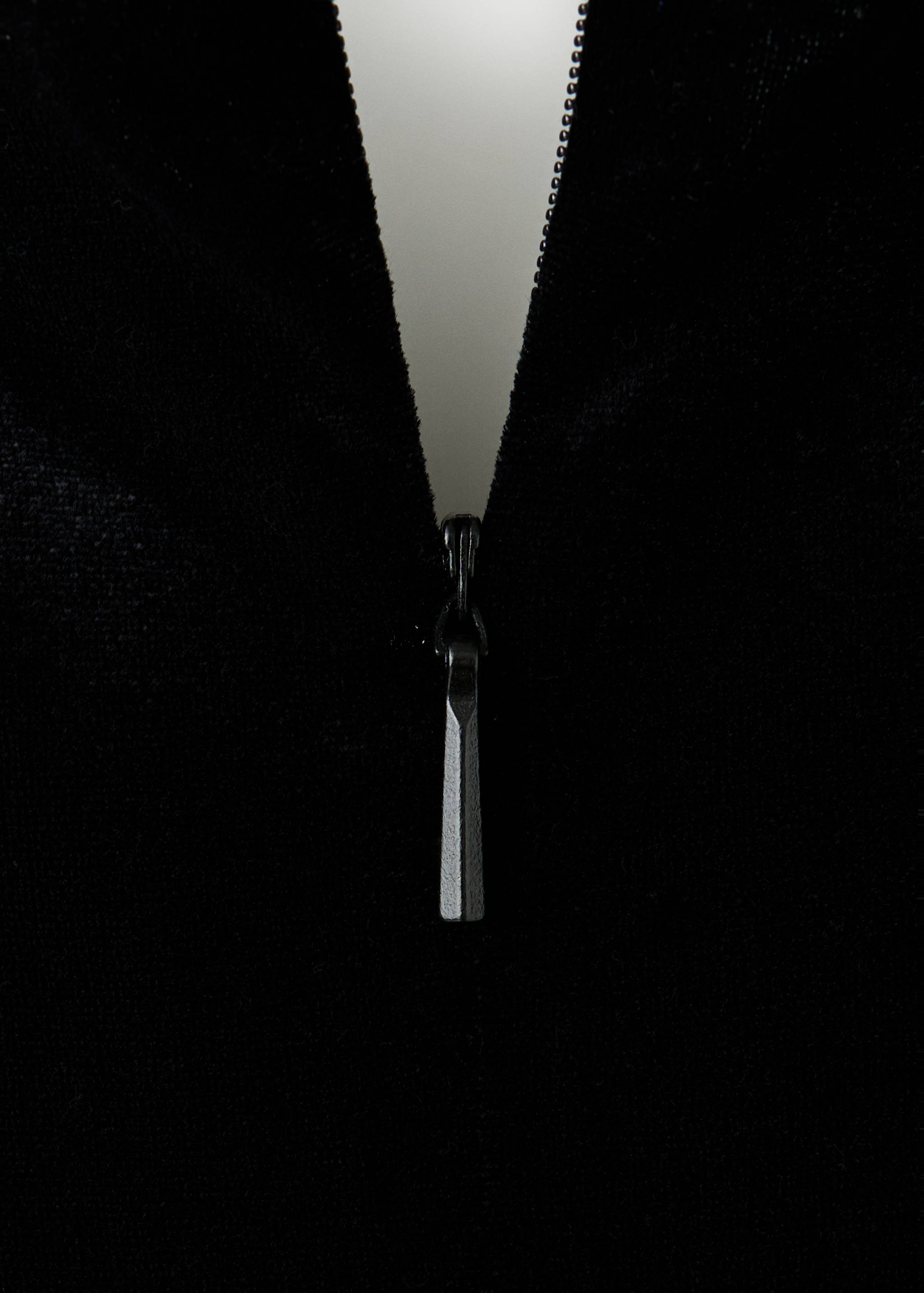 Close-up of a black jumpsuit zipper detail.