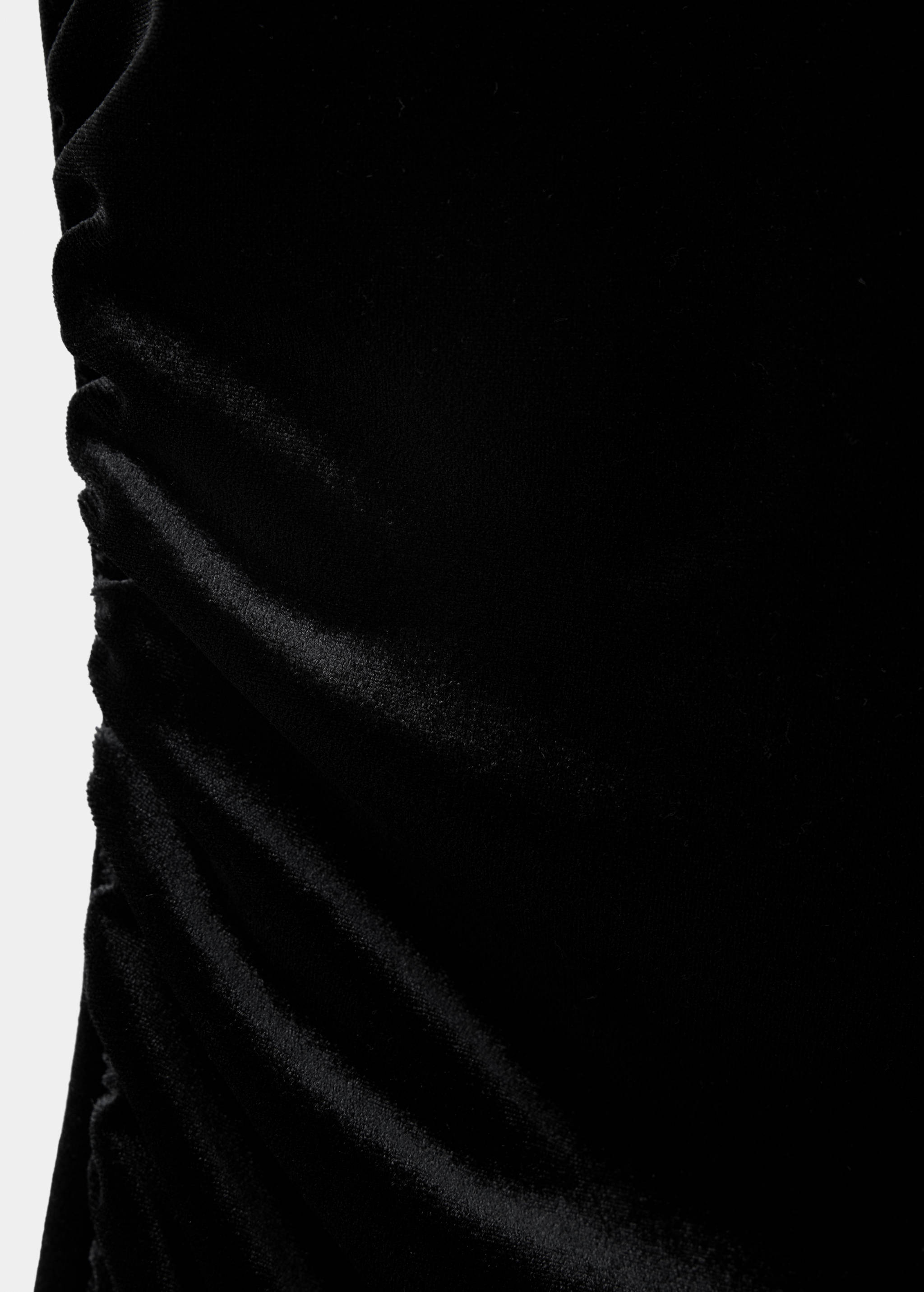 Close-up of a black velvet dress featuring ruched side detail.