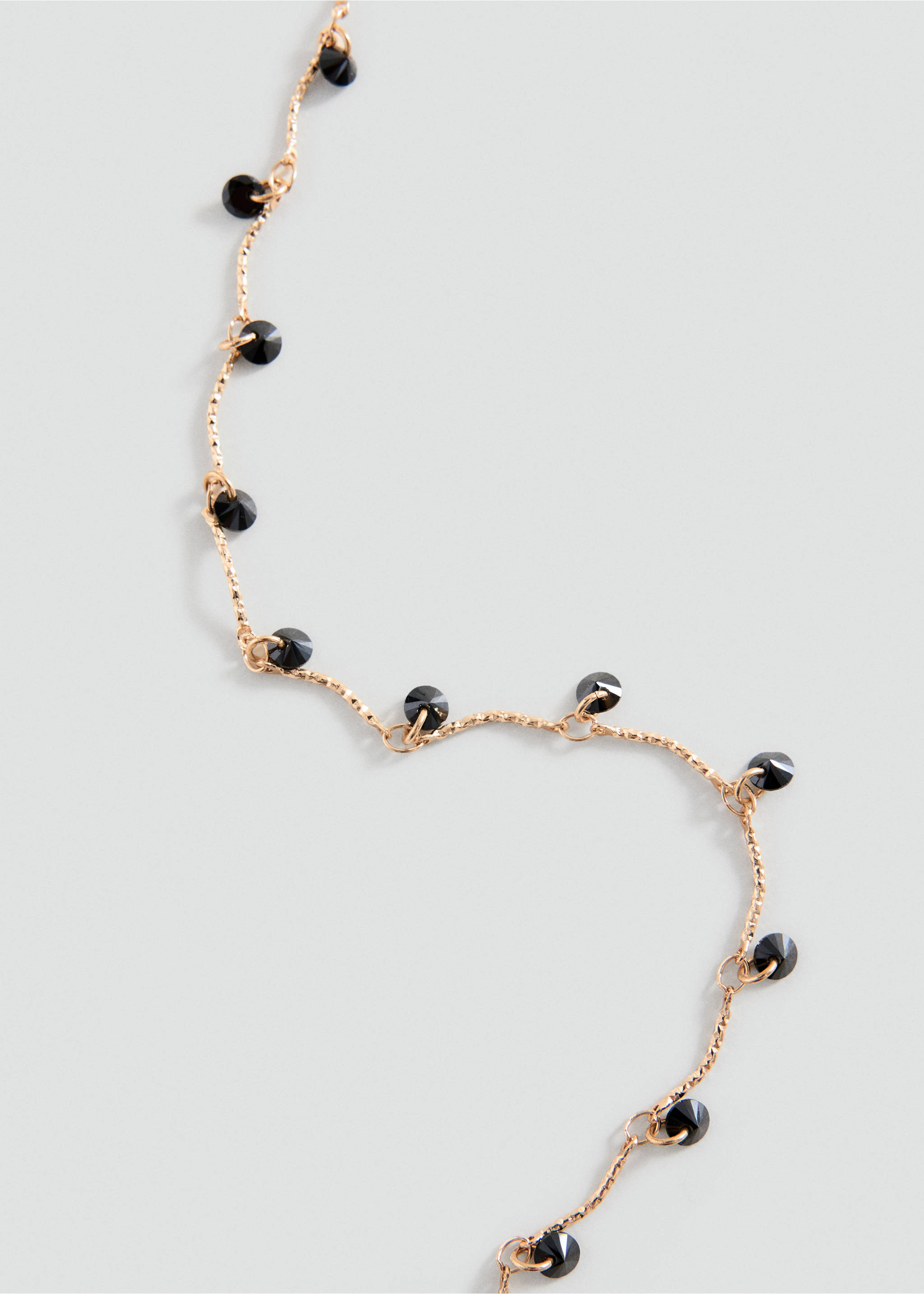 Collar de cadena fino en tono dorado con cuentas negras facetadas en vista de cerca., Oro. Ref: 37069135-00.