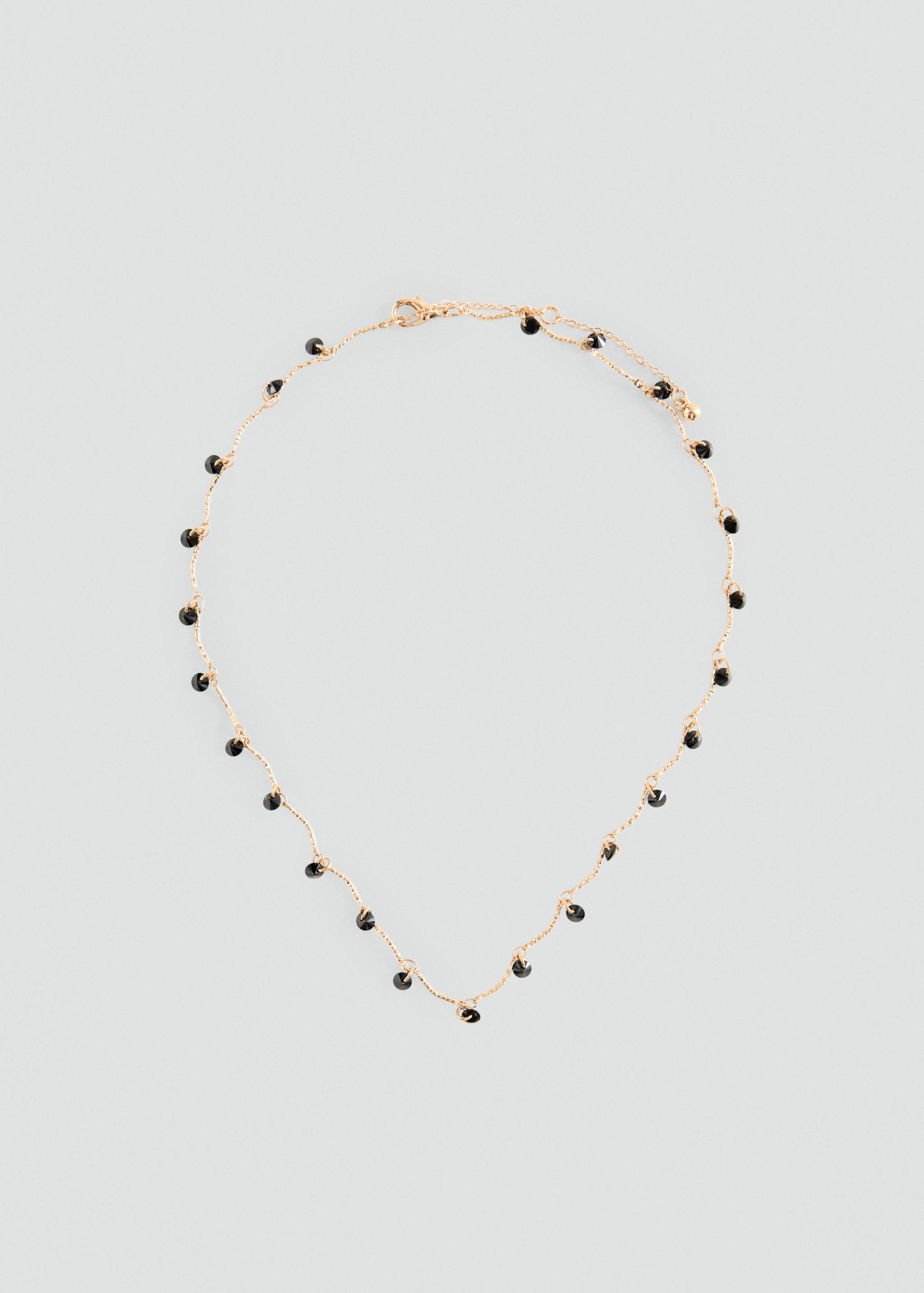 Collar de cadena en tono dorado delicado con abalorios negros colgantes.