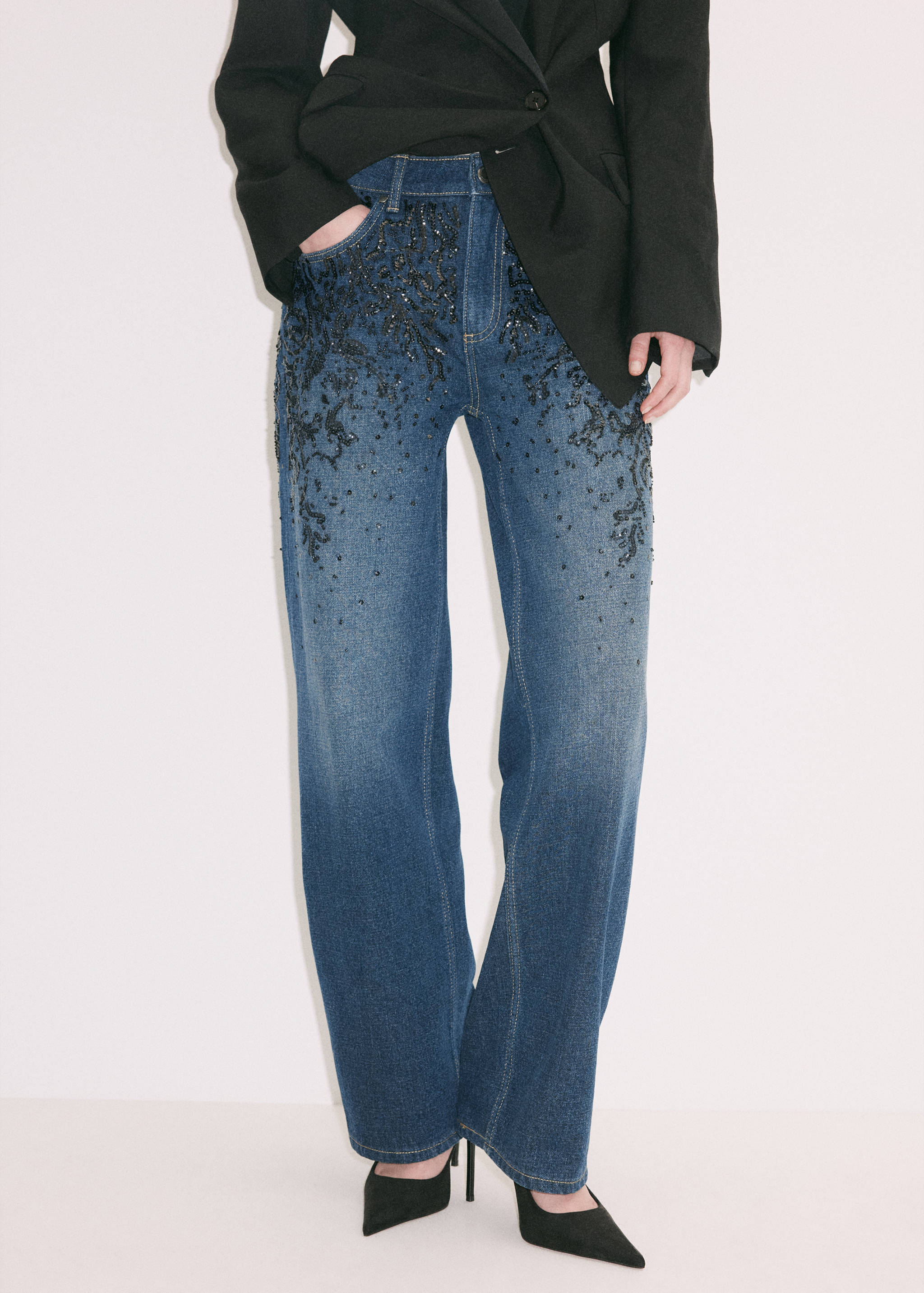 Blue straight-leg denim trousers with black beaded and crystal embellishments.