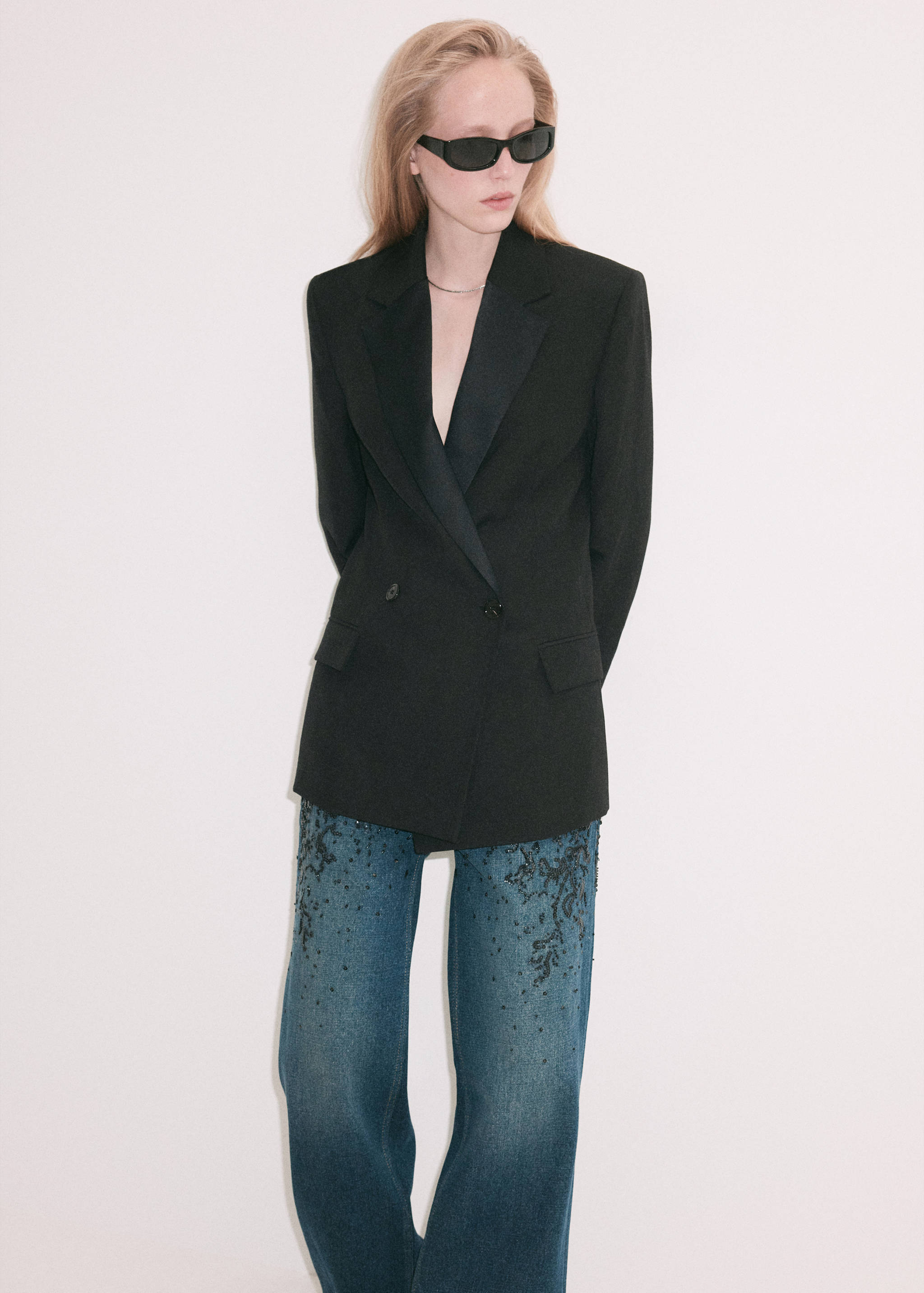 Blue embellished jeans with dark beaded embroidery on the thighs.