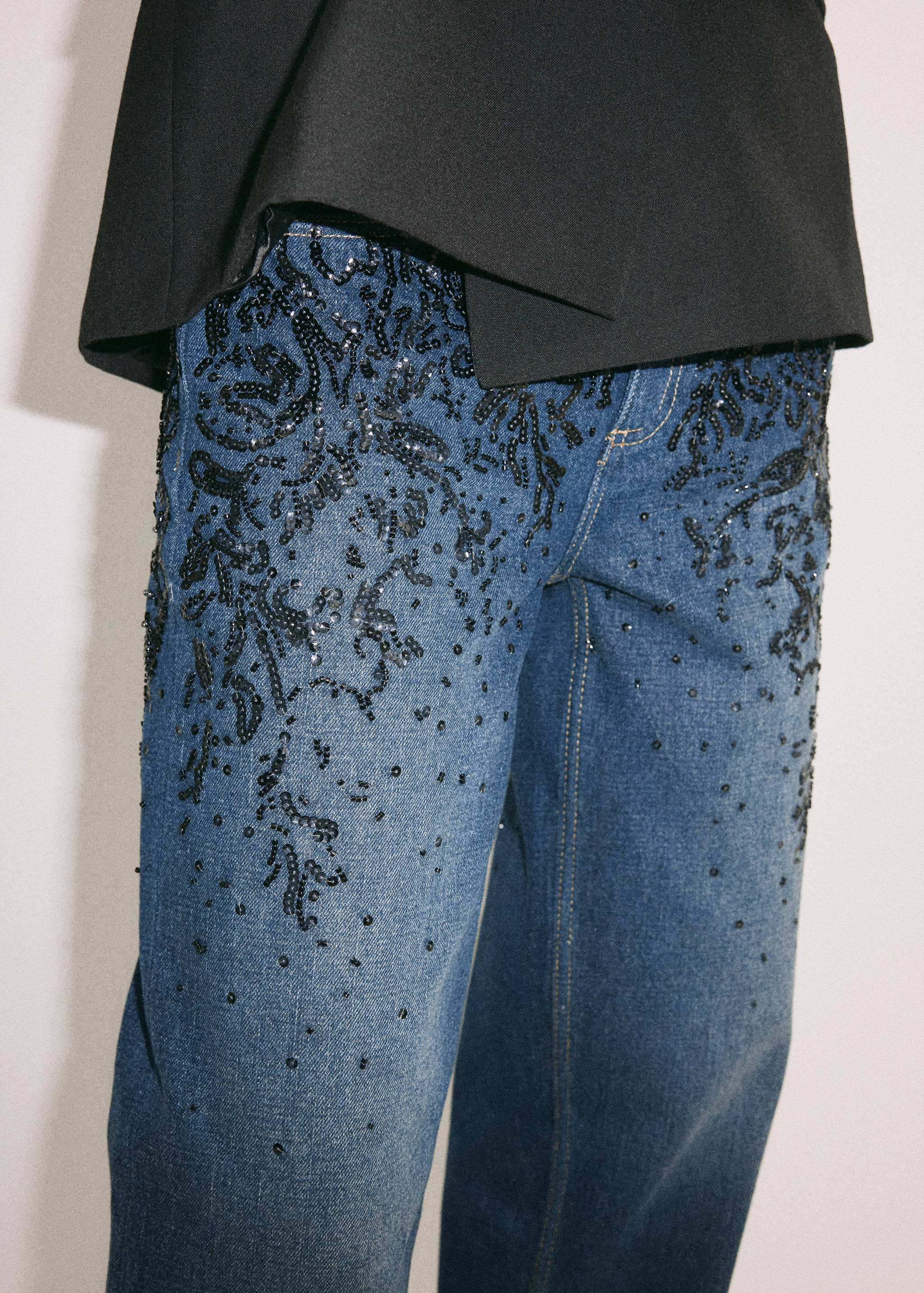 Blue denim trousers with dark sequin embroidery.
