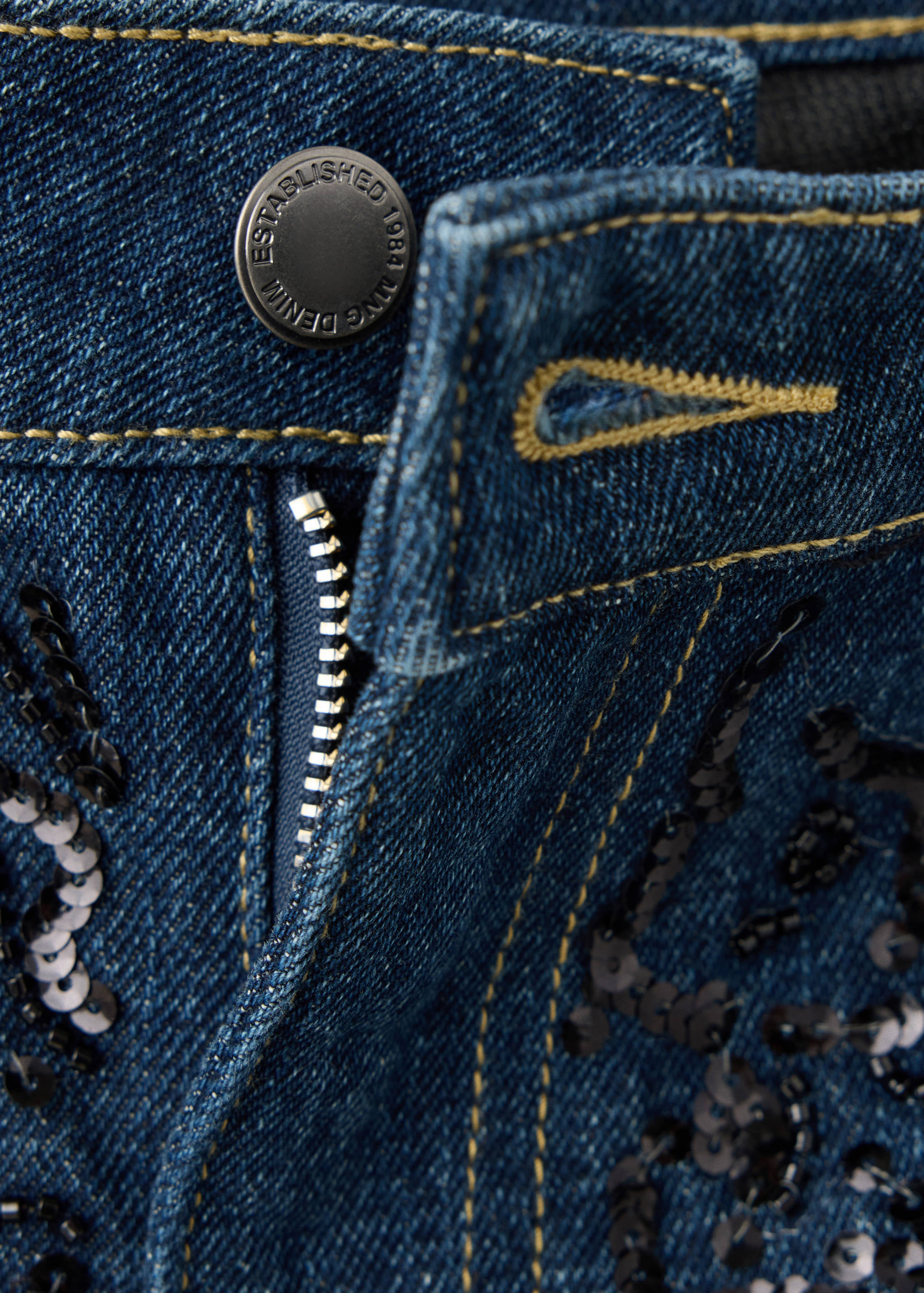 Close-up of sequin-embellished dark blue denim trousers.