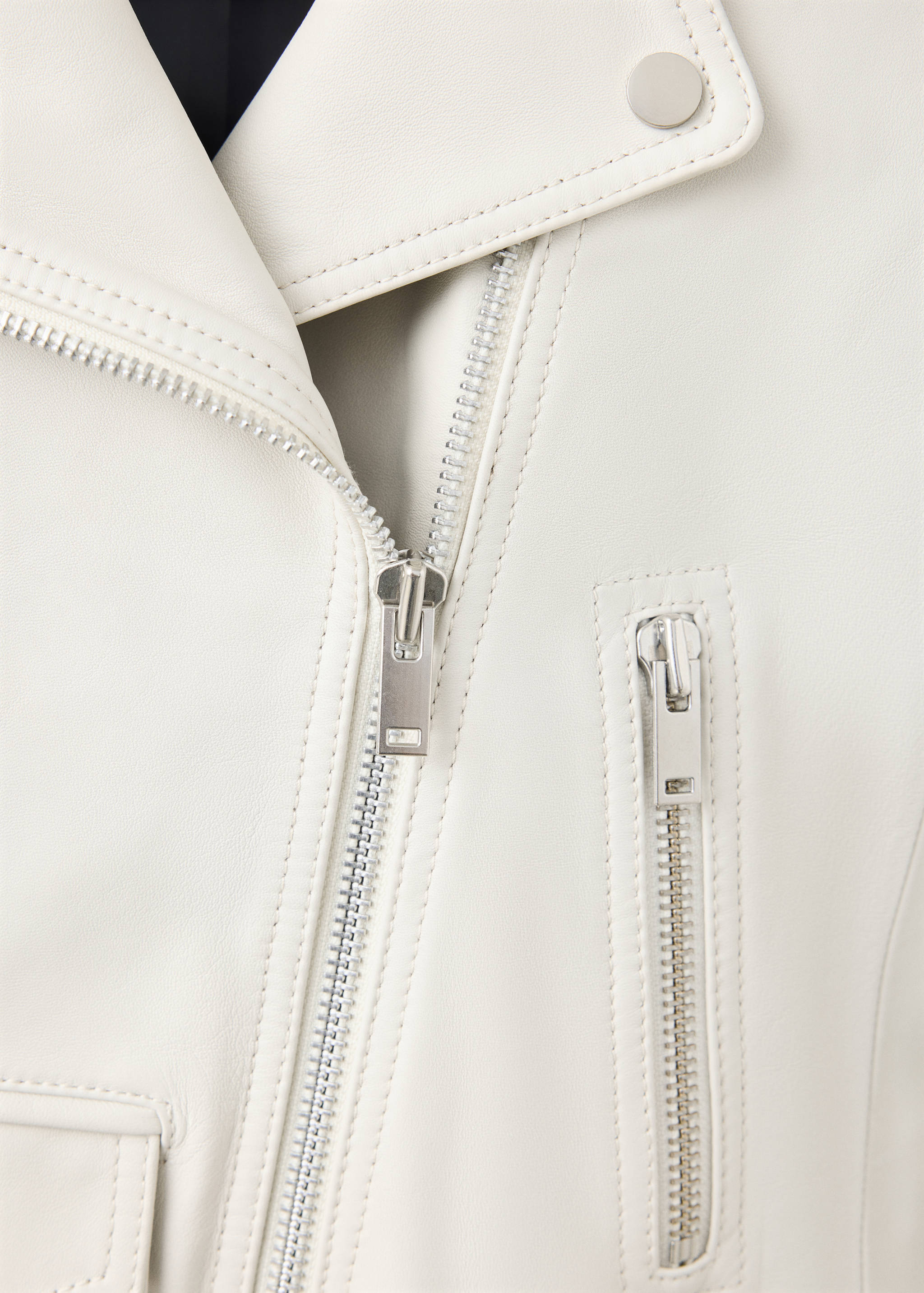 Close-up of an off-white leather biker jacket with silver zips.