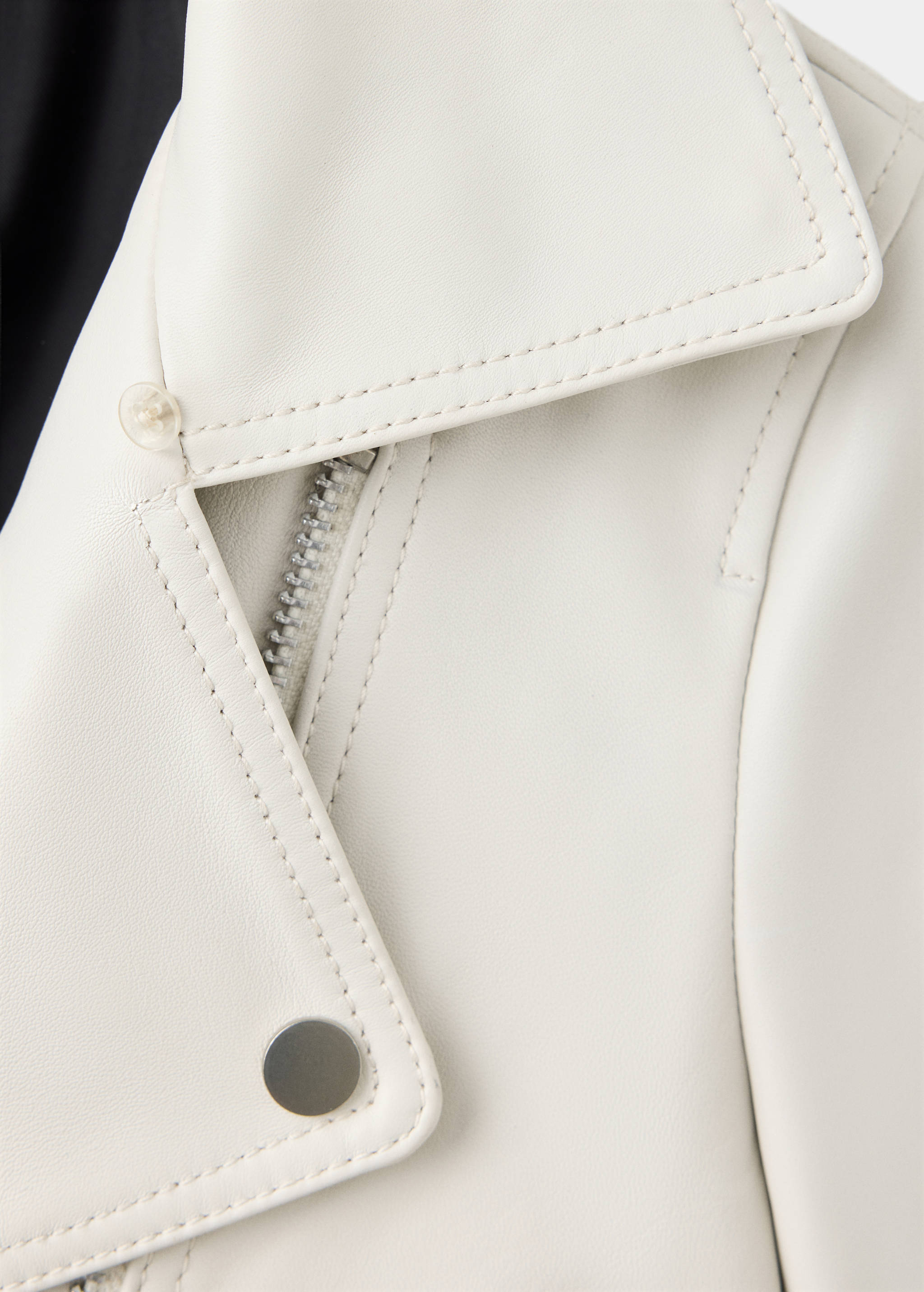 Close-up of white jacket fabric showing collar and metal zipper detail.