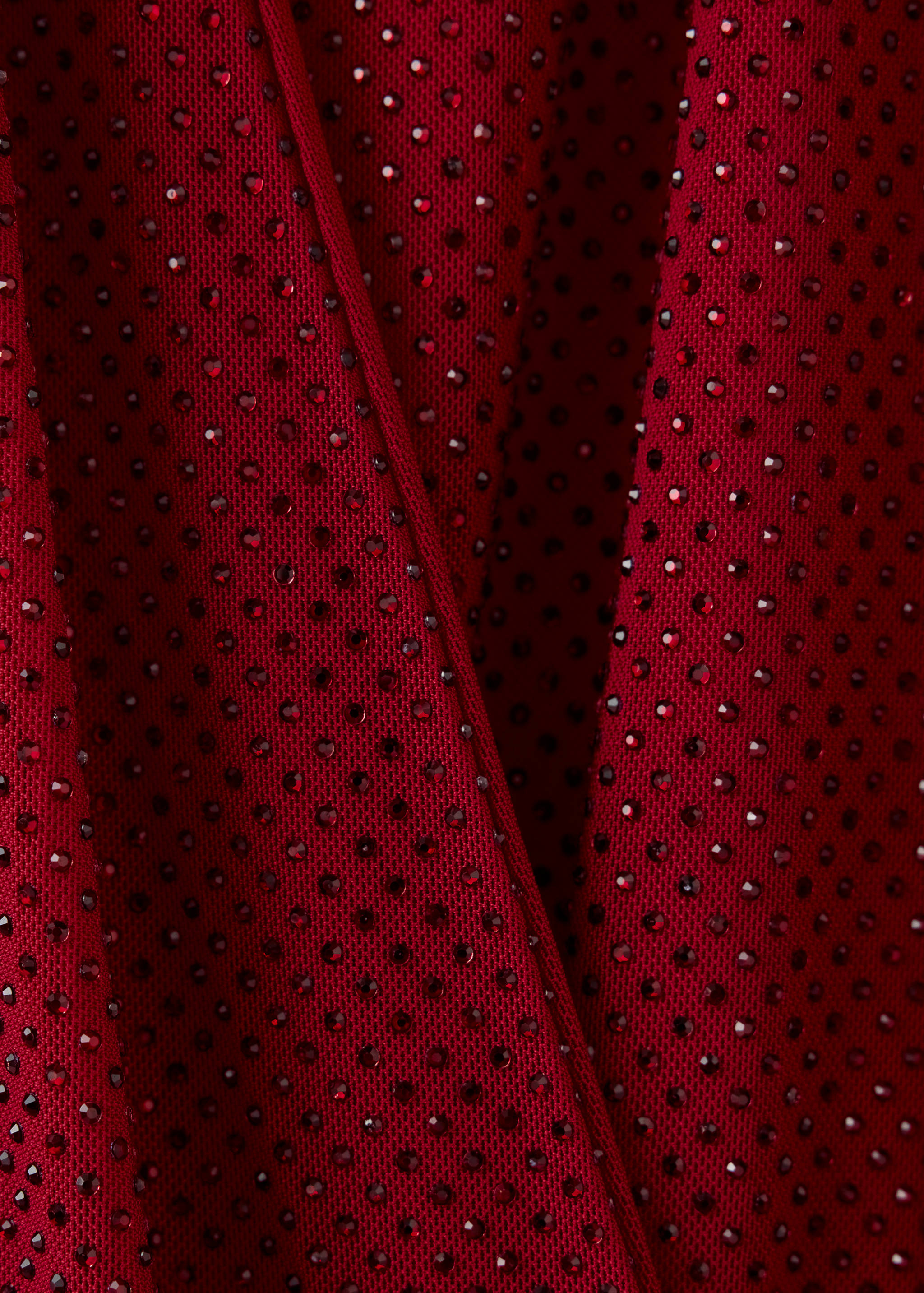 Close-up of a red rhinestone-embellished dress detail.
