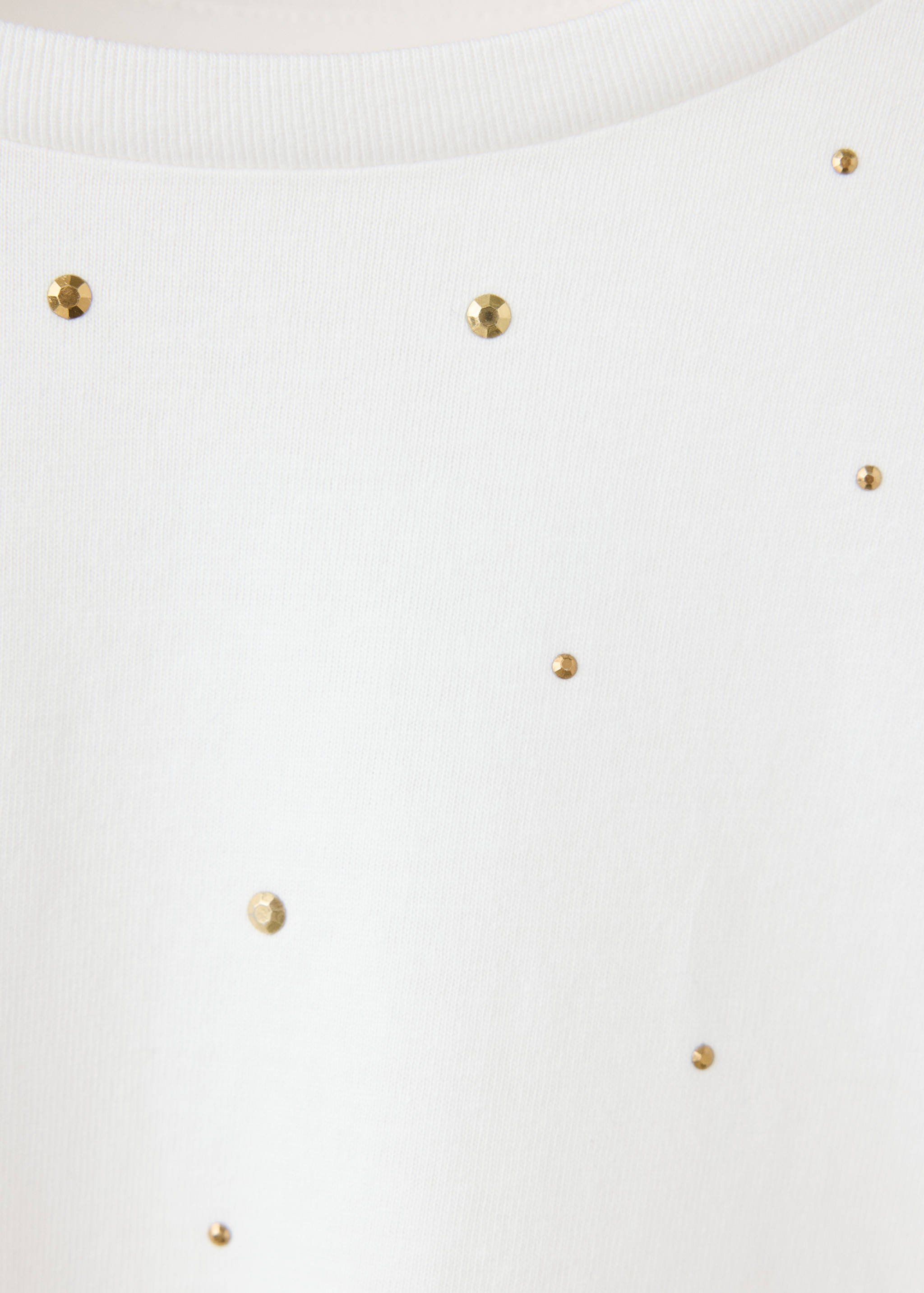 Close-up of a white t-shirt with gold rhinestone details.