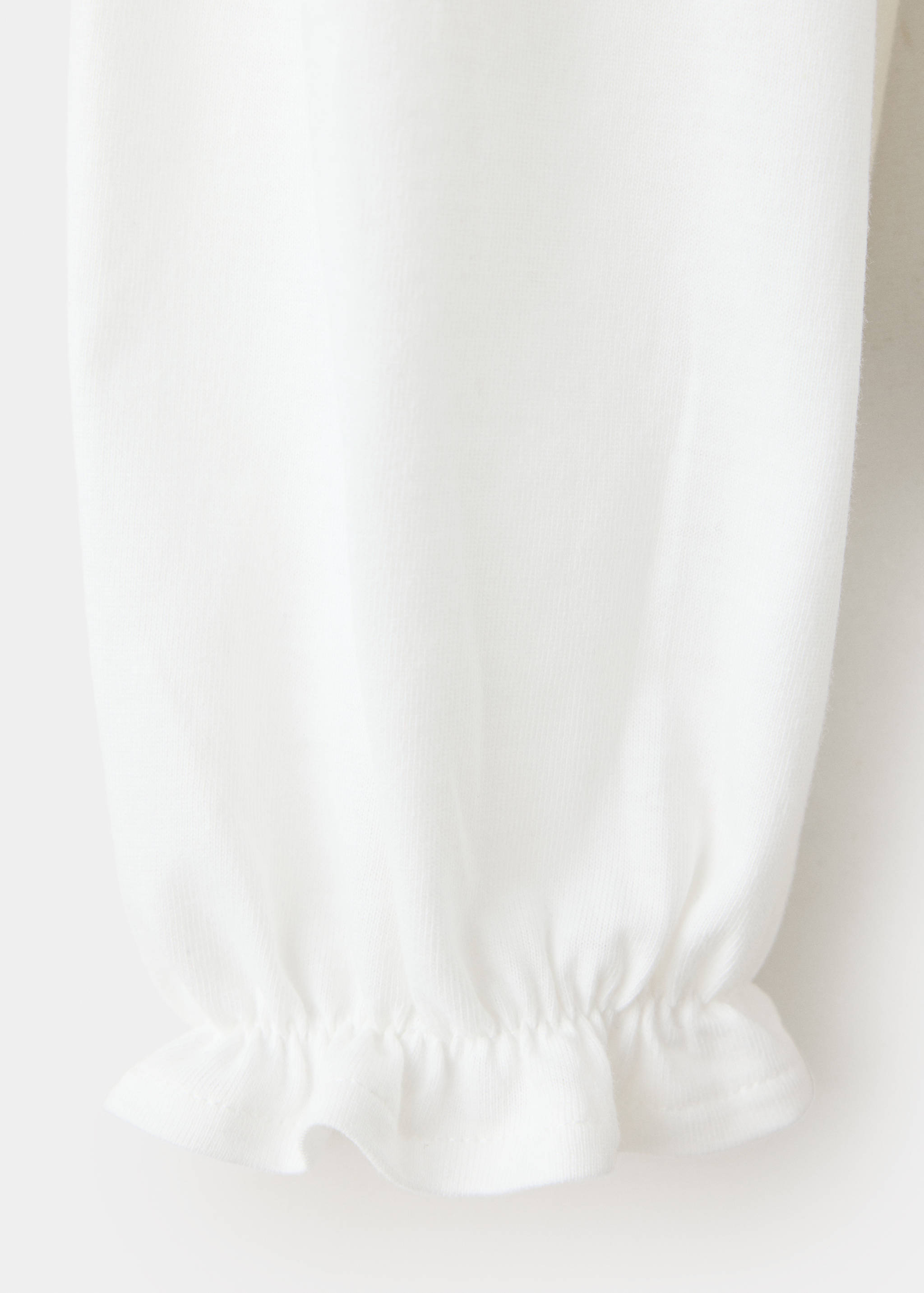 White t-shirt fabric and long sleeve detail with a ruffled cuff.