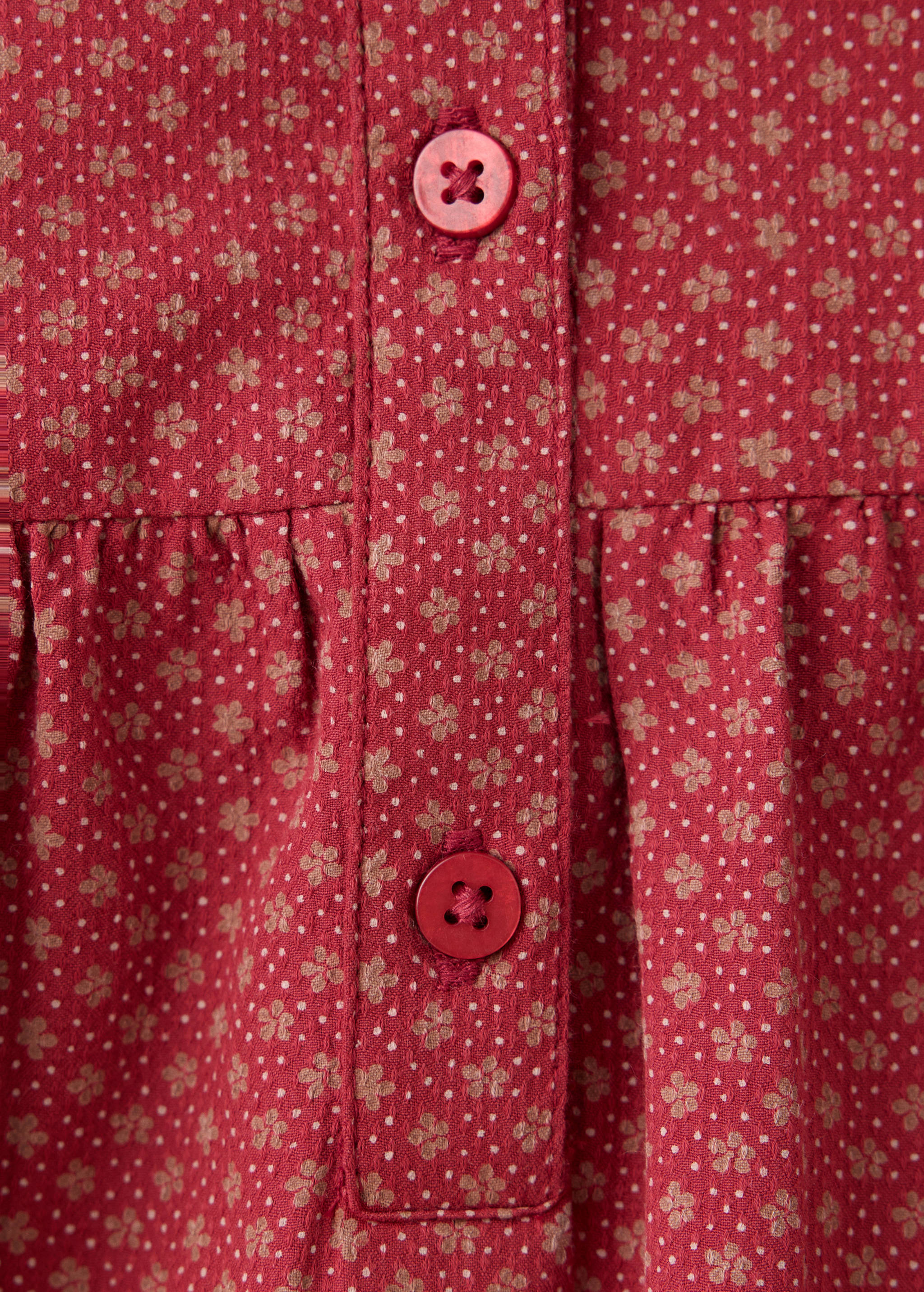 Red floral print dress fabric close-up with a button placket
