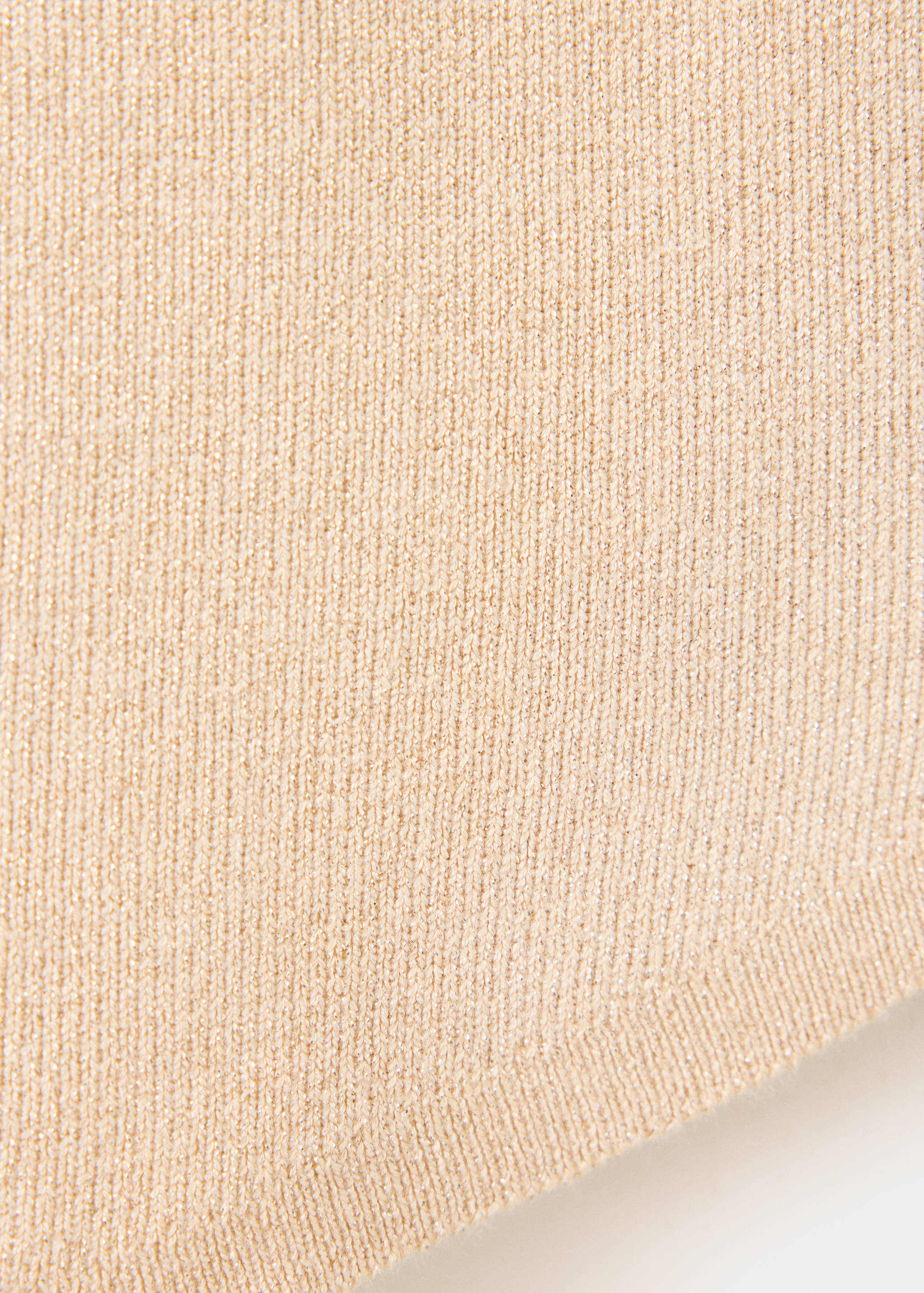 Primer plano de un top de punto canalé beige con acabado metalizado.