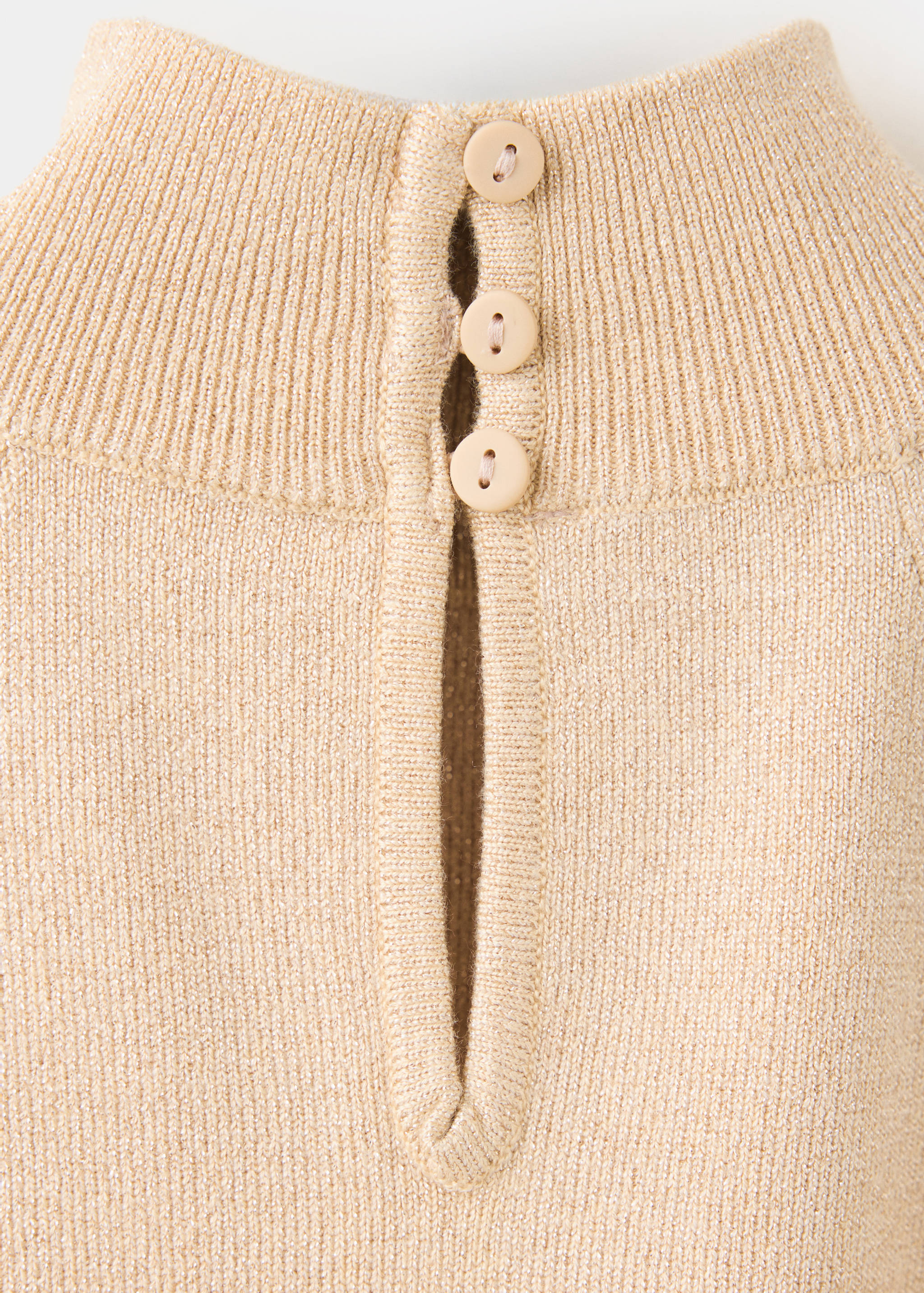 Detalle trasero de tops de punto canalé beige con cierre de botón y abertura lágrima.