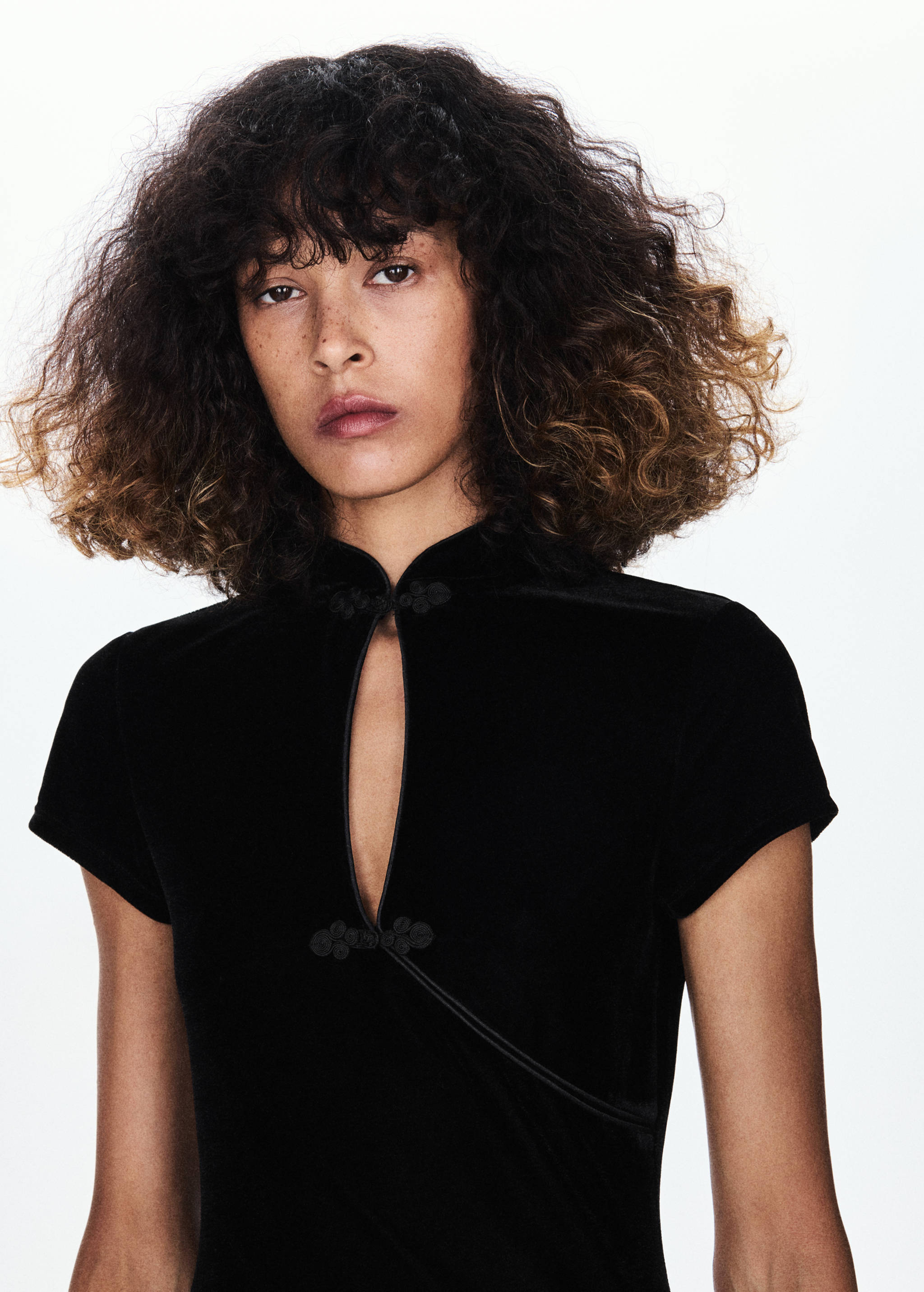 Close-up of a black velvet dress with a Mandarin collar and keyhole neckline.