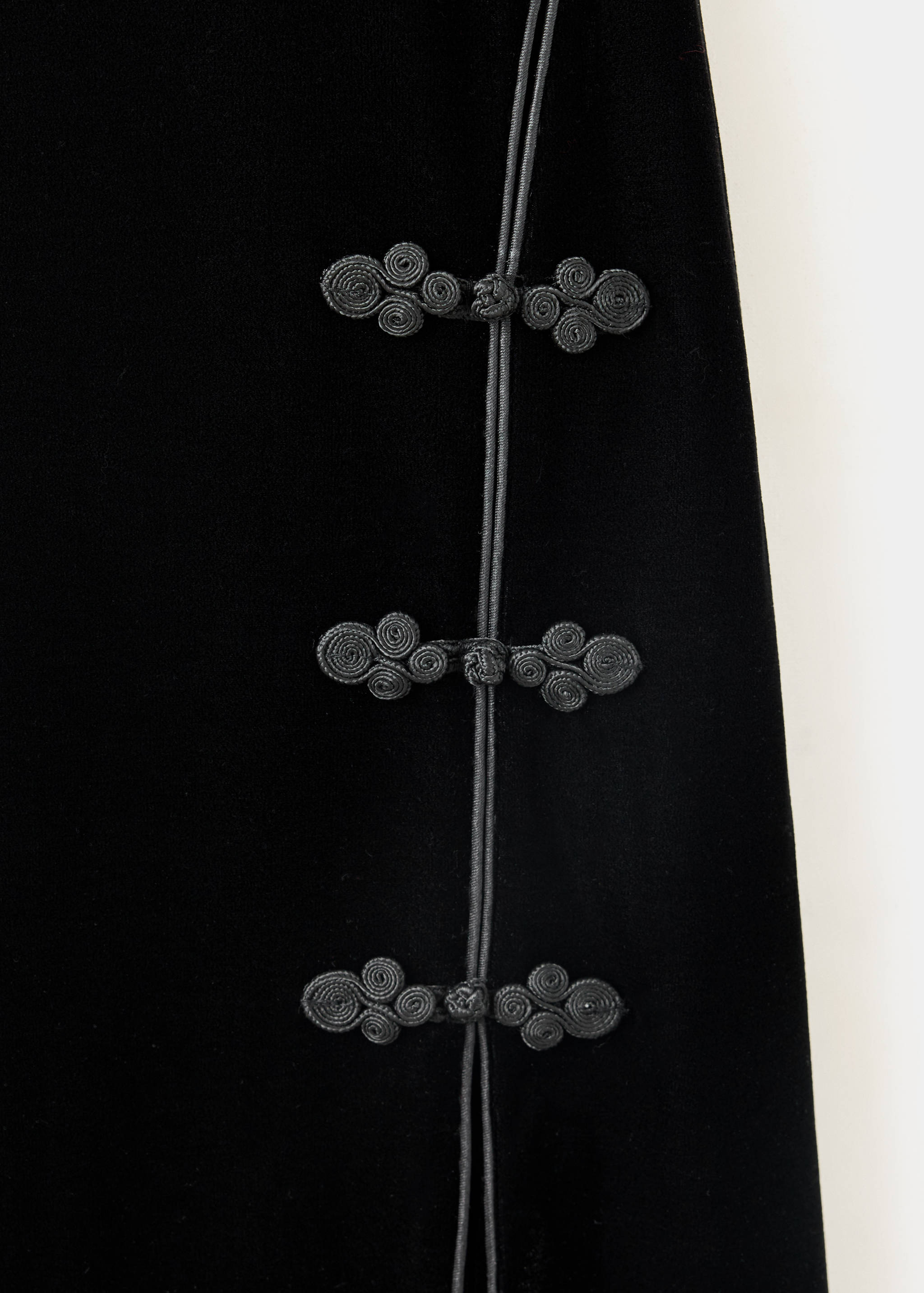 Close-up of black velvet dress with traditional knot closures.