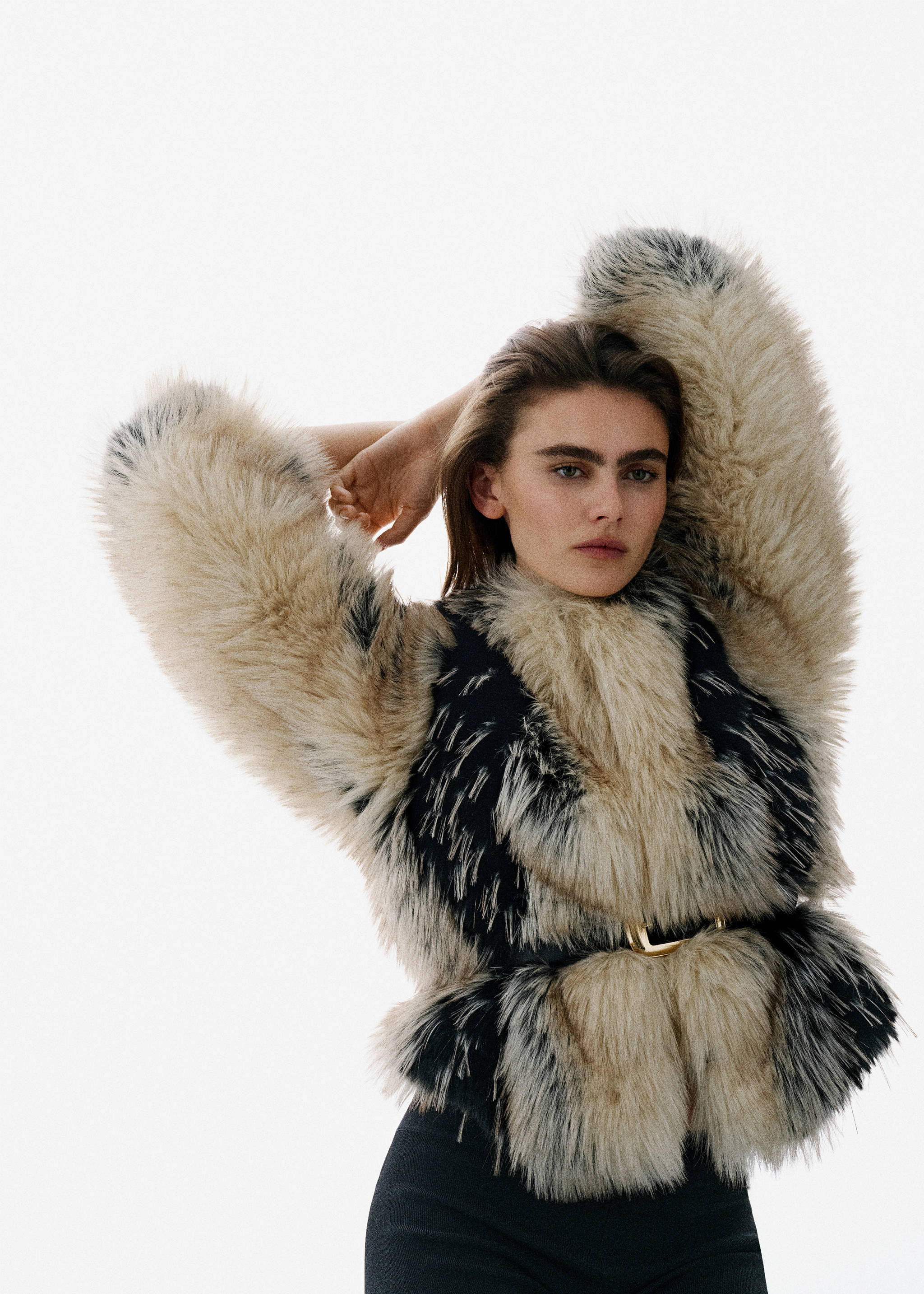 Thin black belt with a gold rectangular buckle cinched over a textured faux-fur garment.