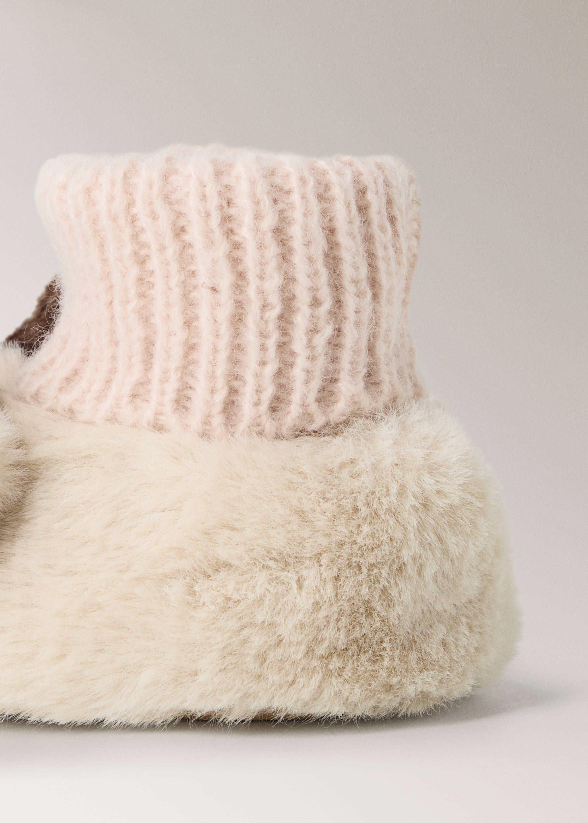 Cream faux-fur house slippers with pale pink ribbed knit cuffs.