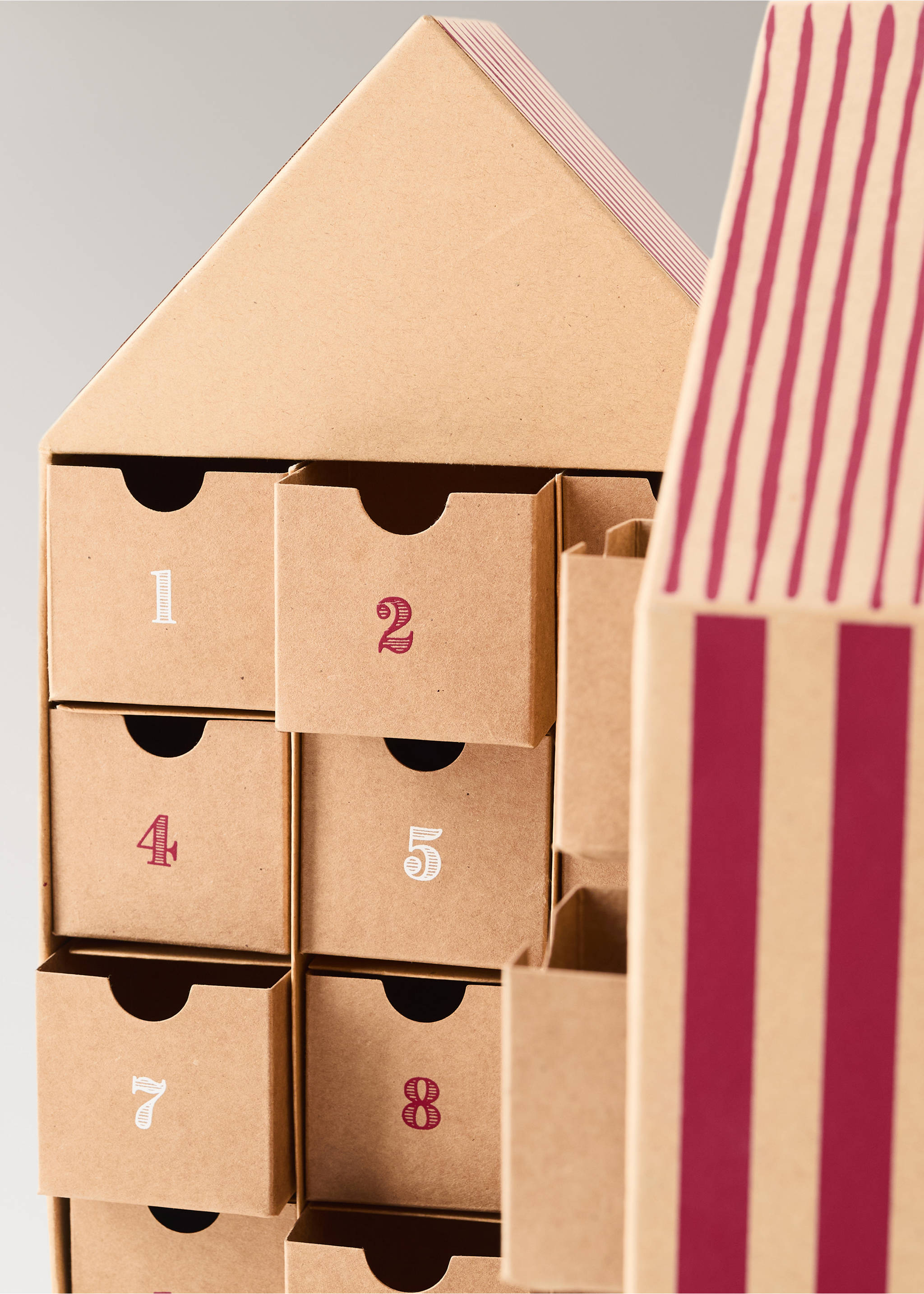 Close-up of a house-shaped brown cardboard advent calendar with numbered drawers and striped roof detail., Brown. Ref: 37071539-00.