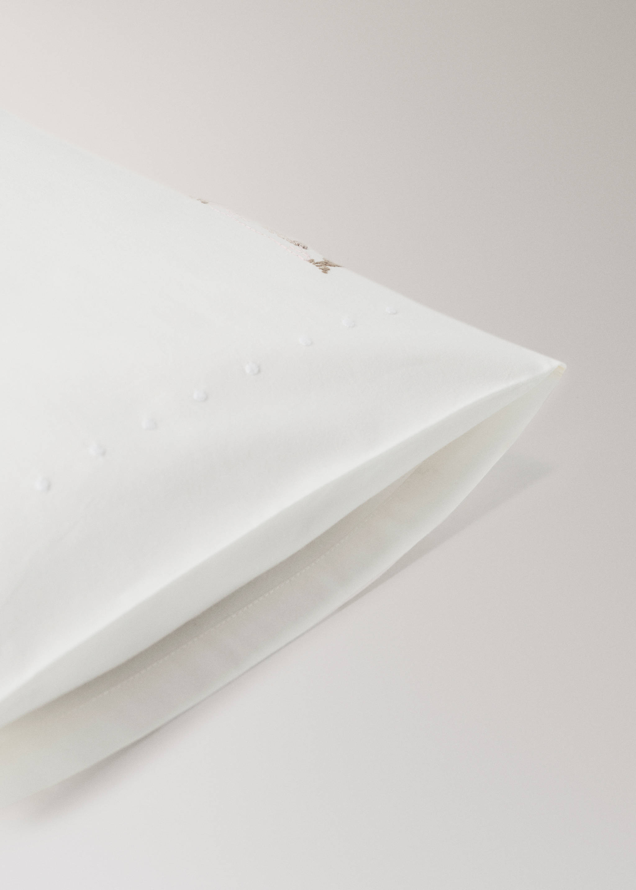 White cot pillowcase with a subtle dotted border detail.