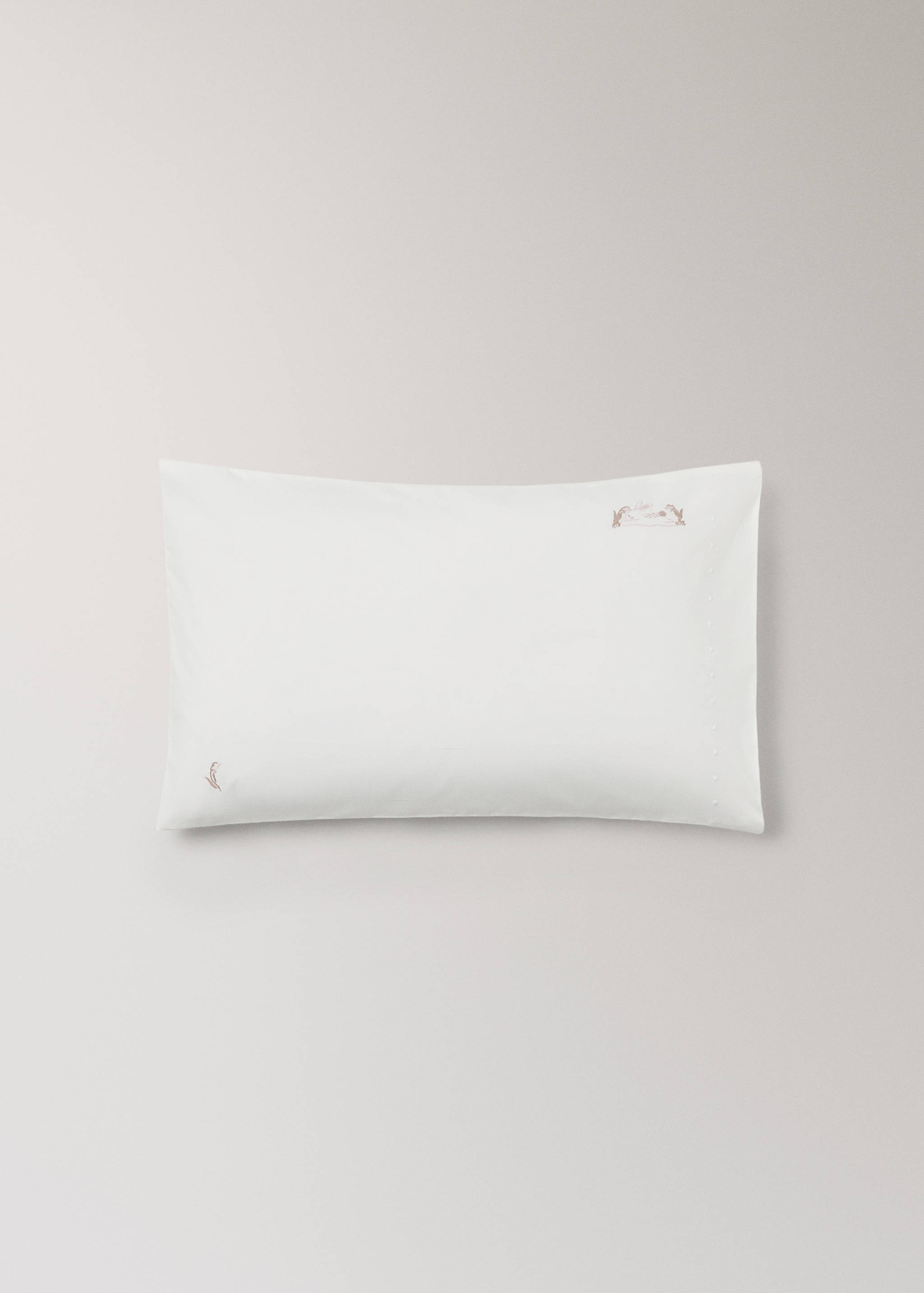 White cot pillowcase with delicate pink embroidery.