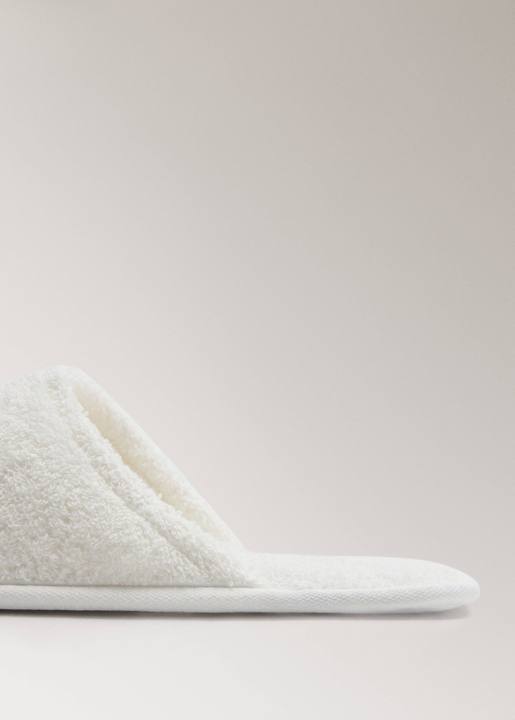 Close-up of a white terry cotton bathroom slipper.