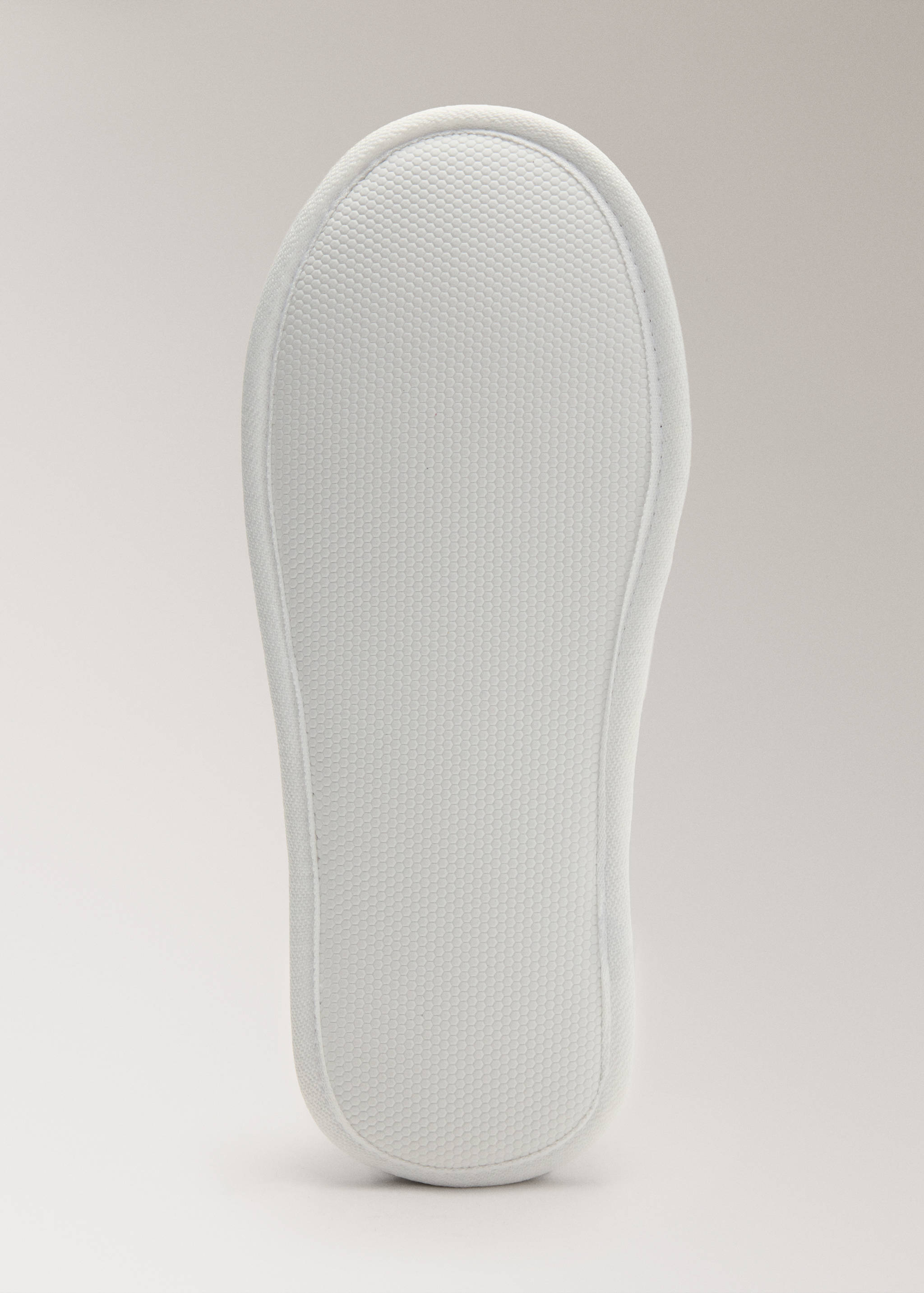 Close-up of a white bathroom slipper sole with textured tread.